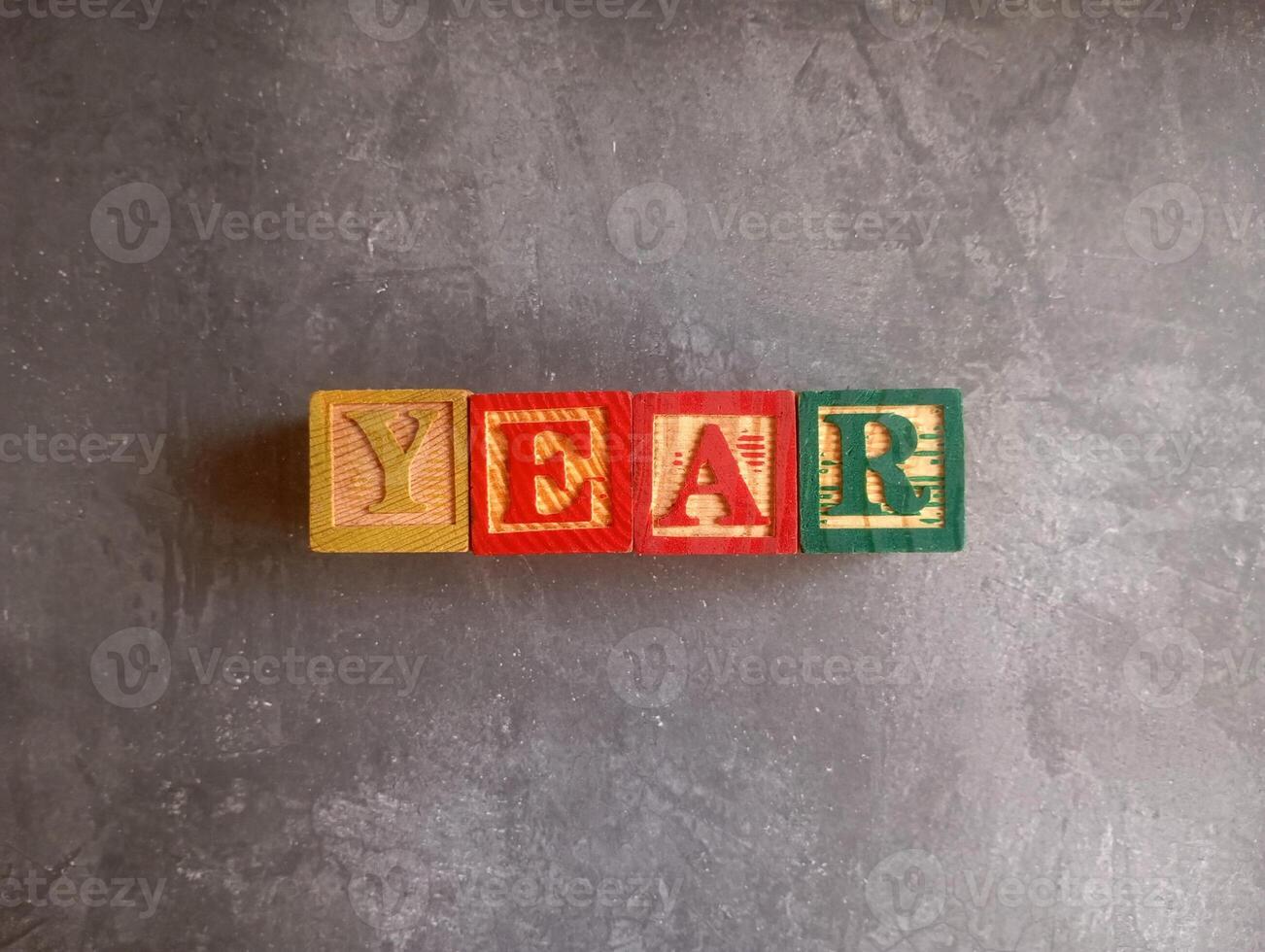 A photo of a wooden block with the words year written on it, styled in isolation with space for text.