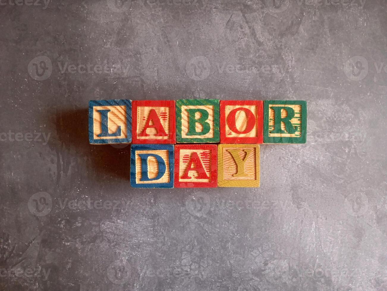 A photo of a wooden block with the words labor day written on it, styled in isolation with space for text.