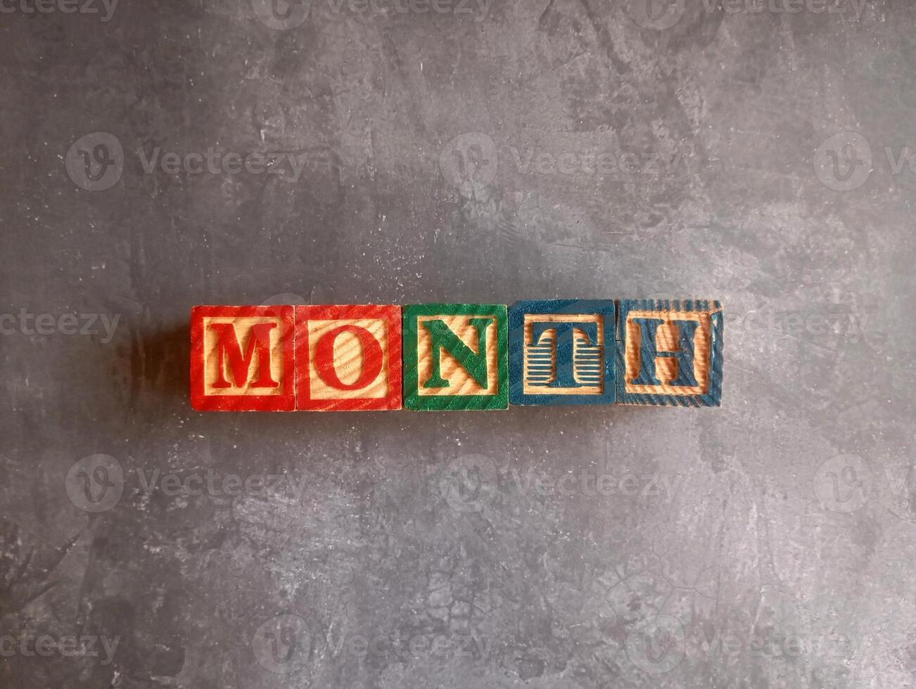A photo of a wooden block with the words month written on it, styled in isolation with space for text.