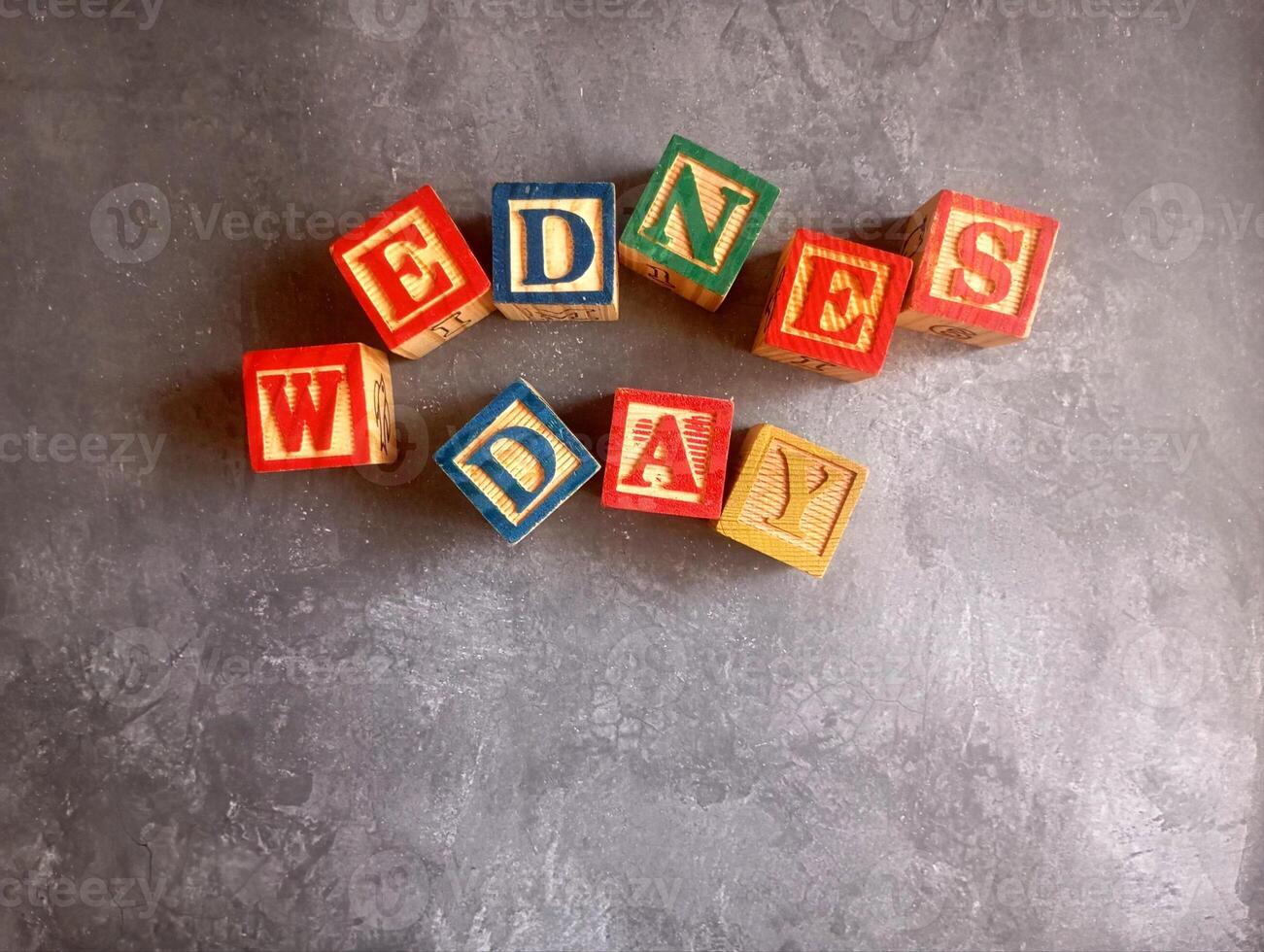 A photo of a wooden block with the words wednesday written on it, styled in isolation with space for text.
