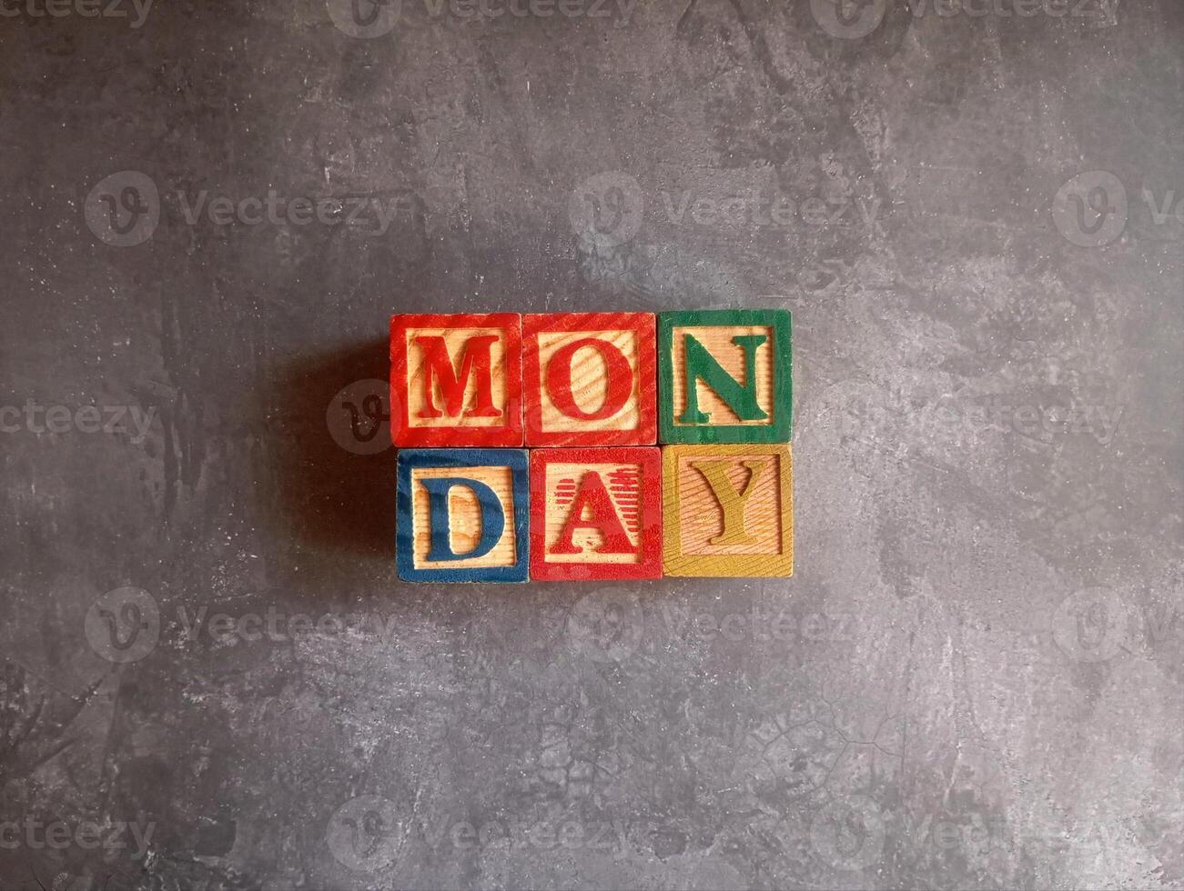 A photo of a wooden block with the words monday written on it, styled in isolation with space for text.