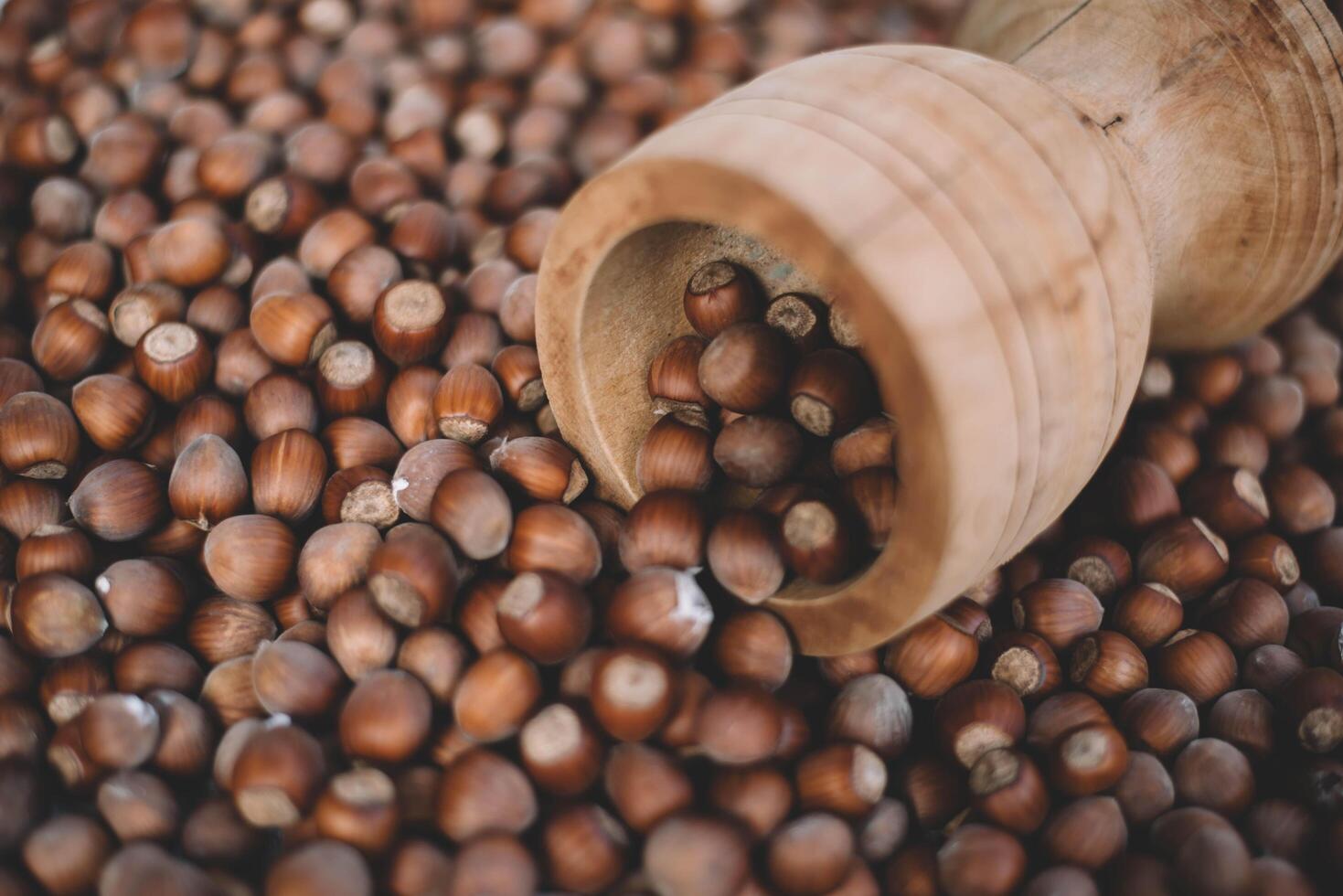 Hazelnuts in a wooden bowl on rustic background, Hazelnut background with green leaf photo
