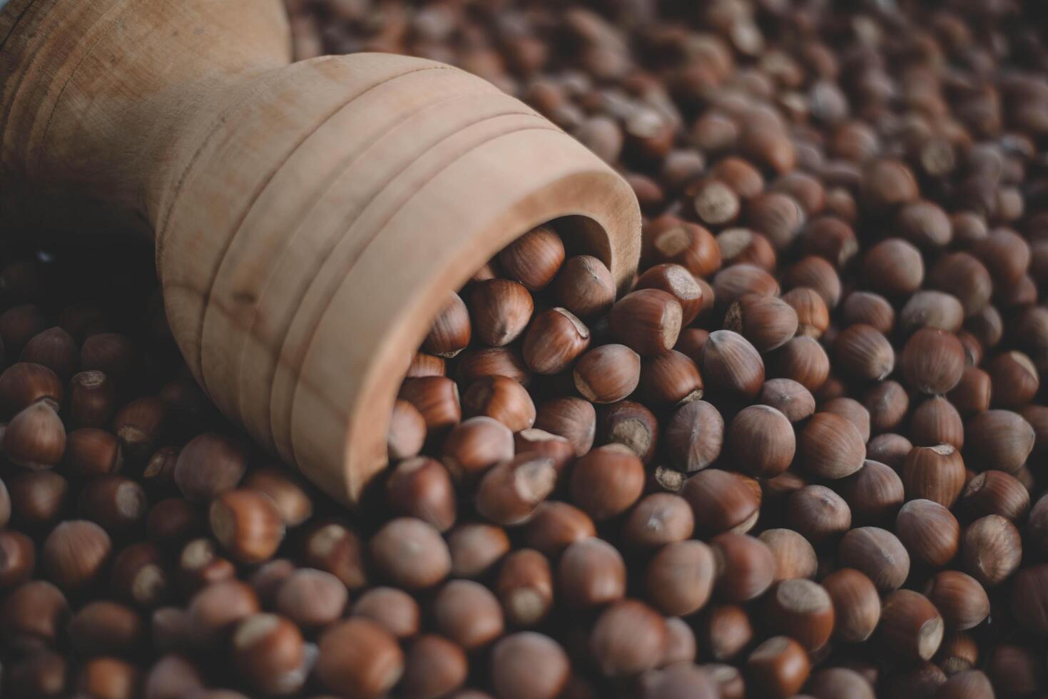 Hazelnuts in a wooden bowl on rustic background, Hazelnut background with green leaf photo