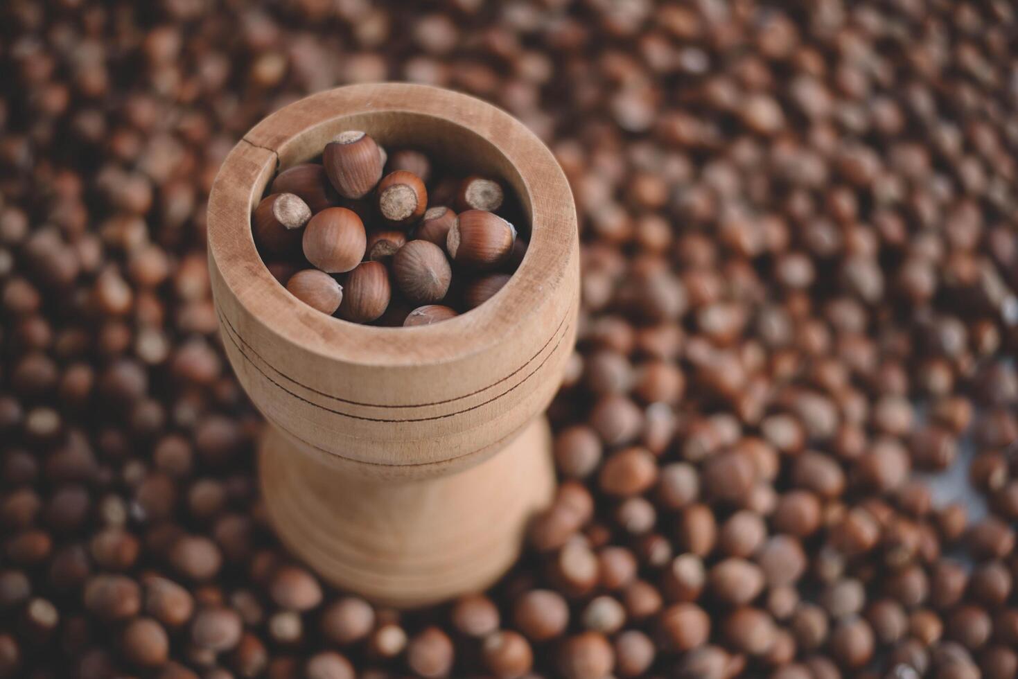 Hazelnuts in a wooden bowl on rustic background, Hazelnut background with green leaf photo