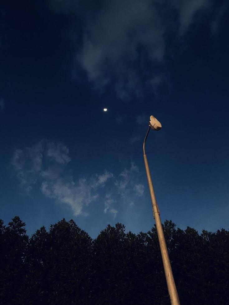 a street light and a moon in the sky photo