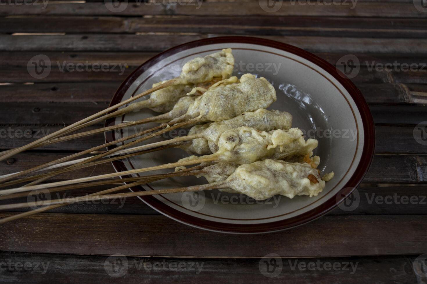 A plate of sempol, a type of fried food made from tapioca flour dough, shaped into ovals and skewered, with a chewy texture, eaten with spicy red sauce and soy sauce or peanut sauce can be added. photo