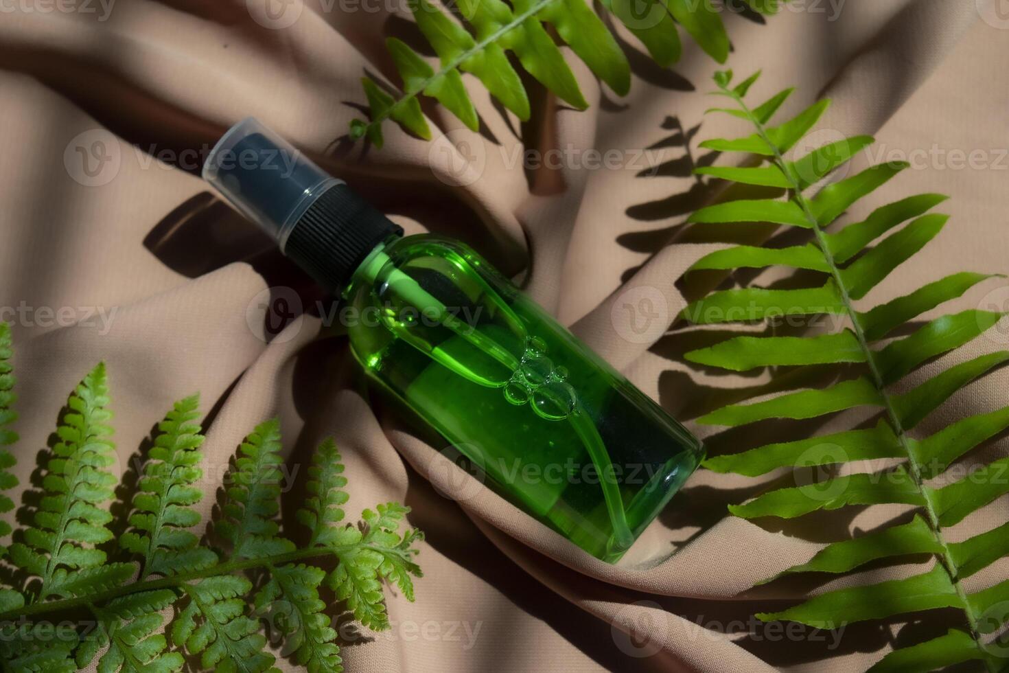 A bottle of beauty product with some fern leaves on a cloth. Flat lay product photography concept. photo