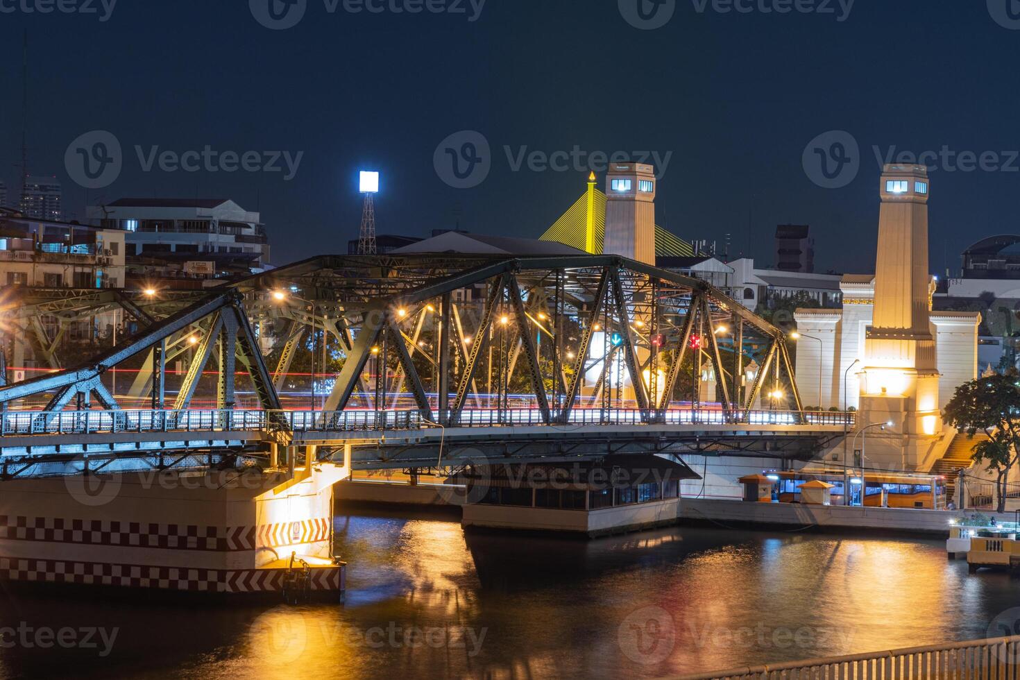 illuminated bridge at night reflects beautifully on water, showcasing vibrant cityscape. scene captures essence of urban life and architectural design photo