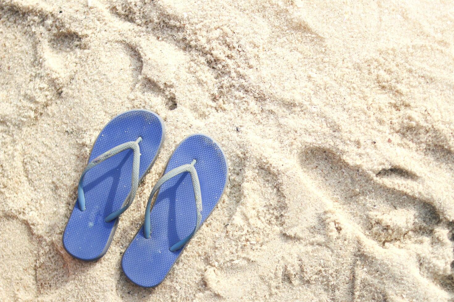 A pair of blue flip flops on a sandy beach photo