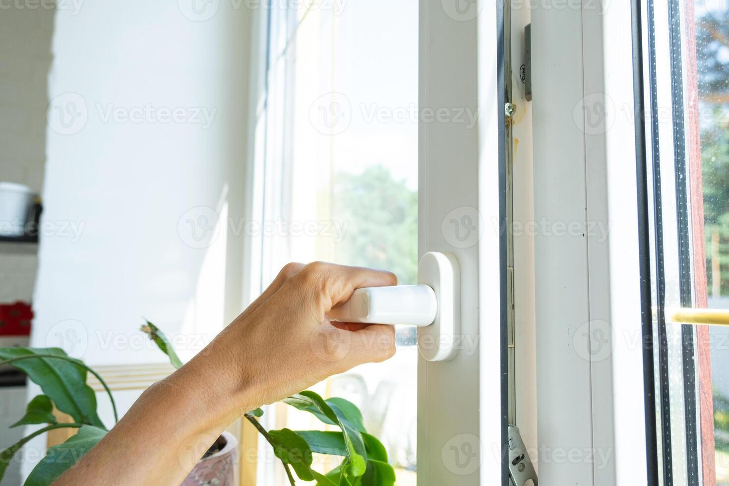 The hand holds the handle of a plastic double-glazed window, closing and opening the window with a rotary mechanism, the position of the handle for ventilation, micro-ventilation photo