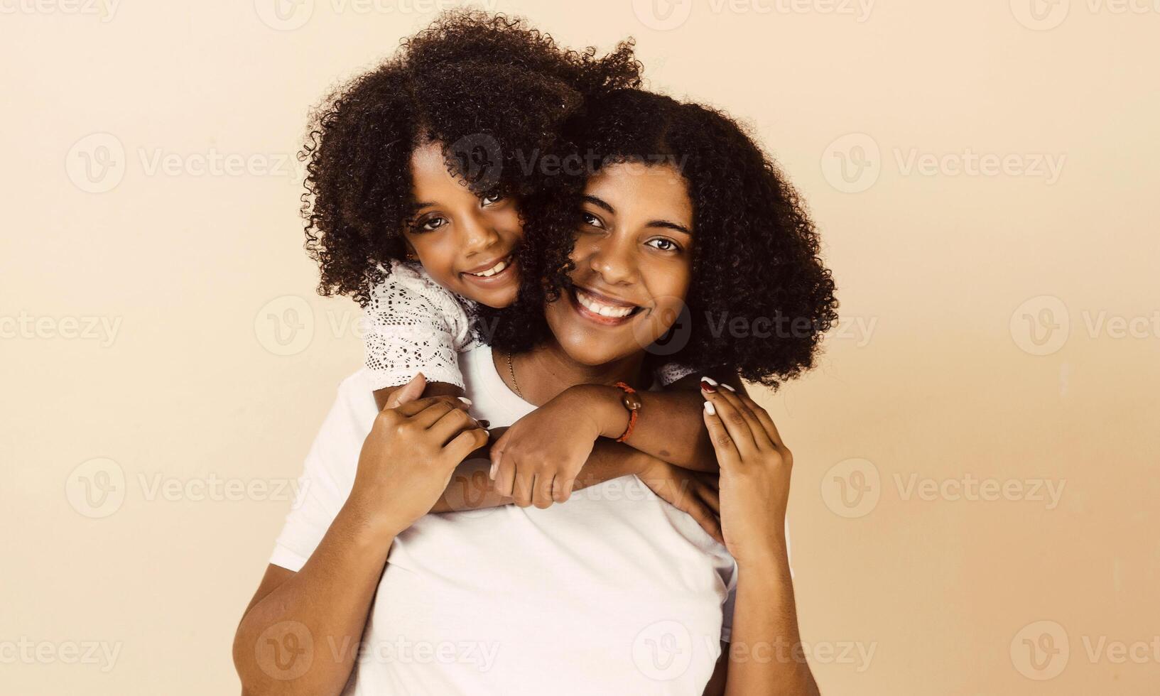 afro american mother and daughter smiling happy hugging over isolated background. photo