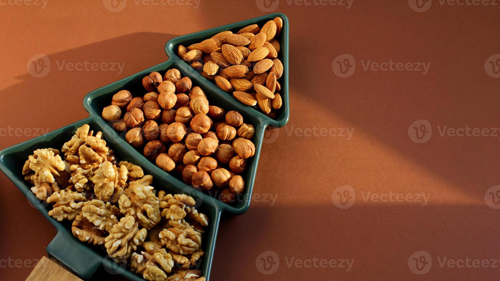 different types of nuts, Various snacks for the New Year table in a plate in the shape of a Christmas tree. photo