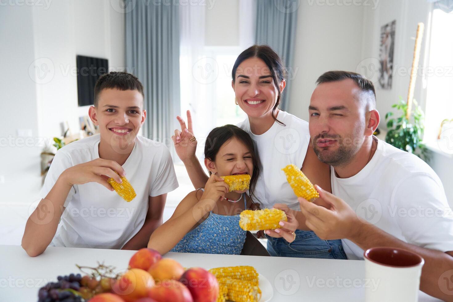 Family enjoying corn on the cob at a cozy dining table in a bright, modern home photo