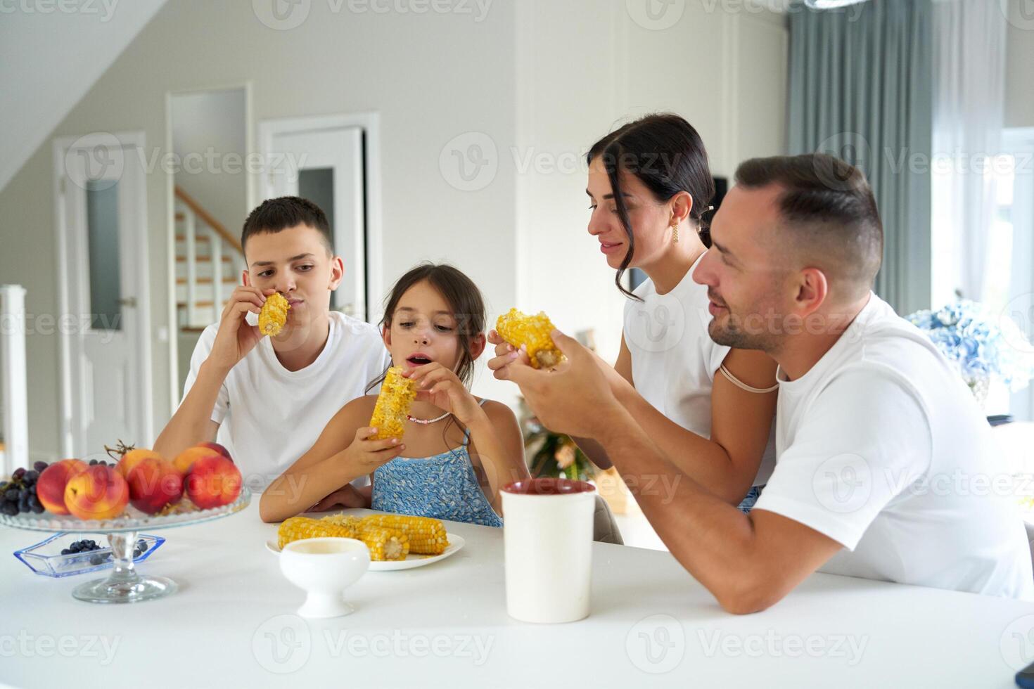 Family enjoying sweet corn together in a cozy dining room during a sunny afternoon photo