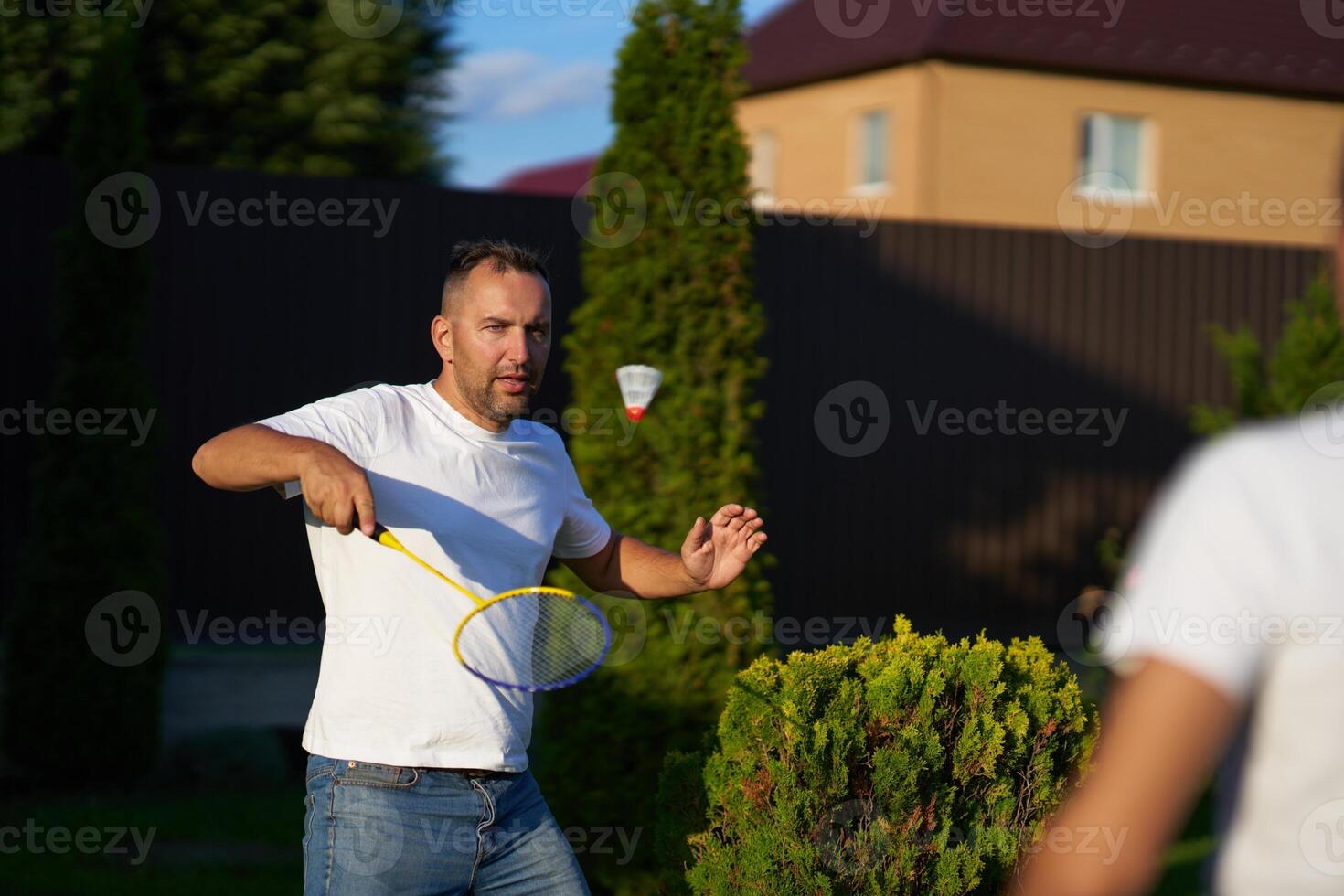 Man playing badminton outdoors in a backyard during sunny weather photo