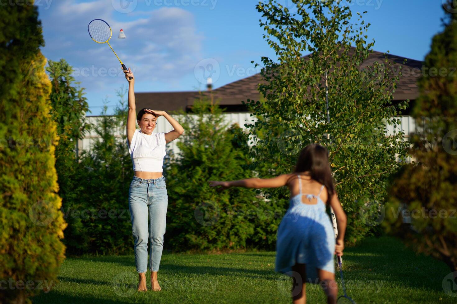 Women playing badminton in a sunny backyard during late afternoon photo