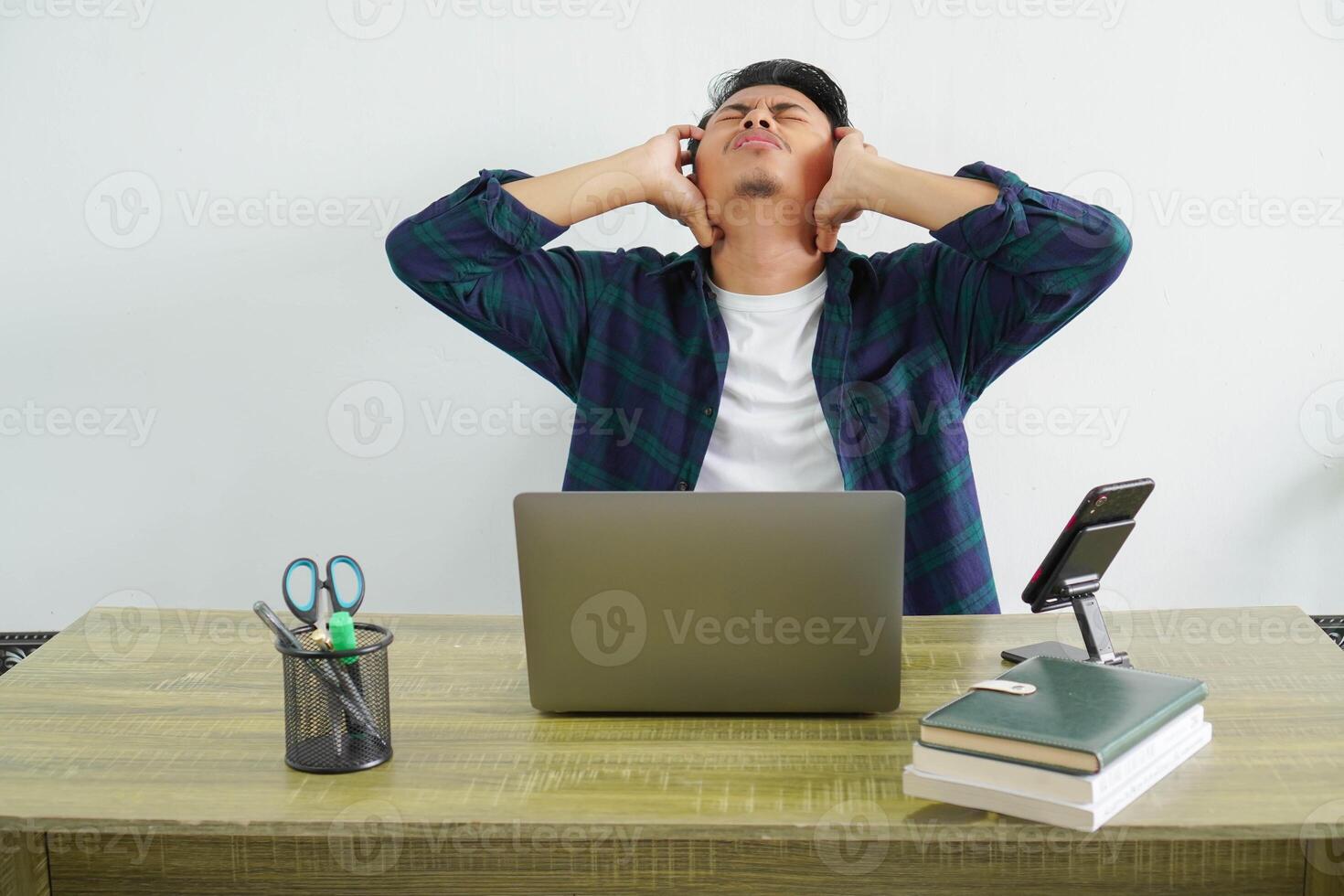frustrated asian businessman is sitting at his workplace photo