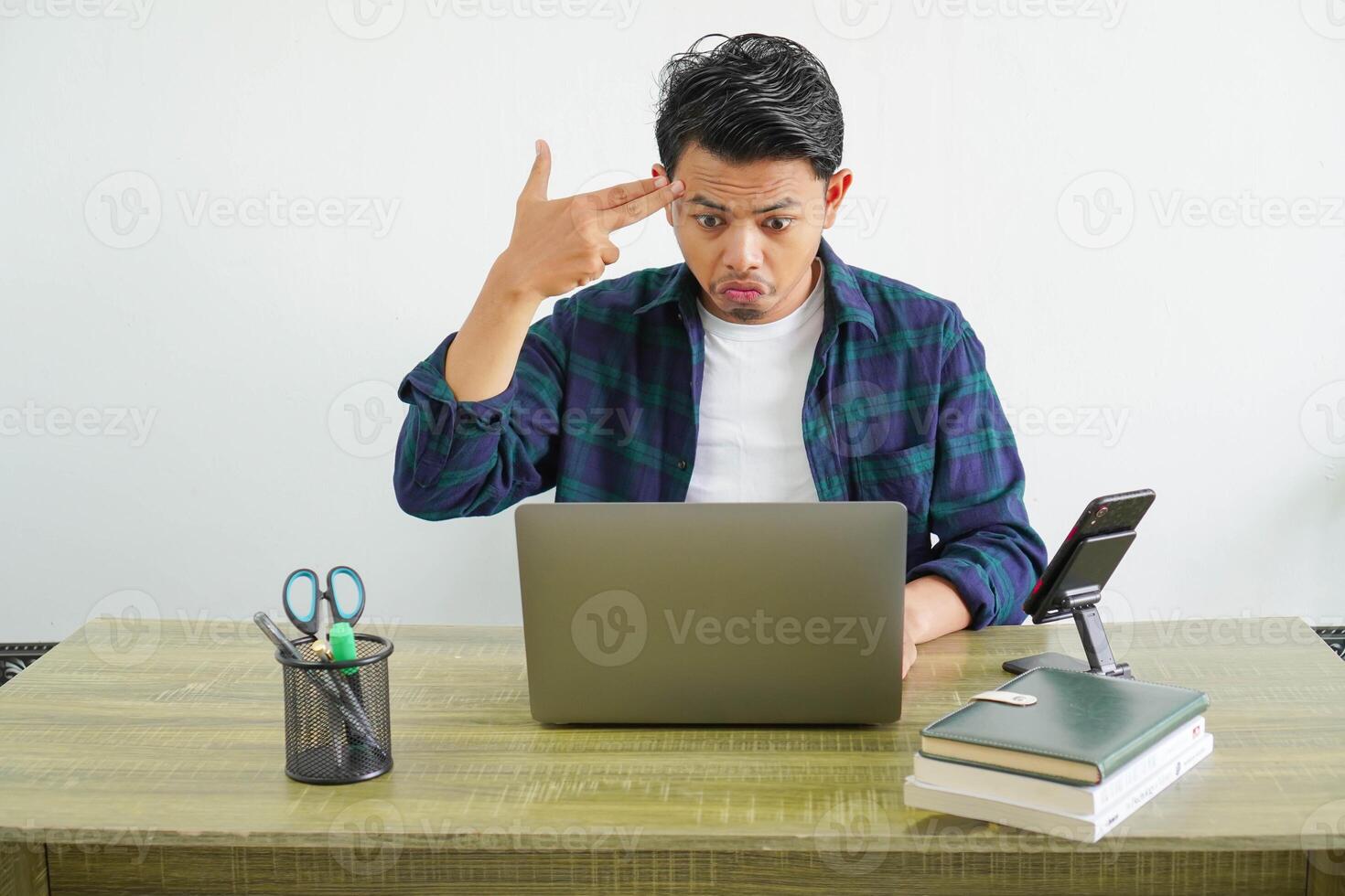freelancer asian man in workplace making suicide gesture photo