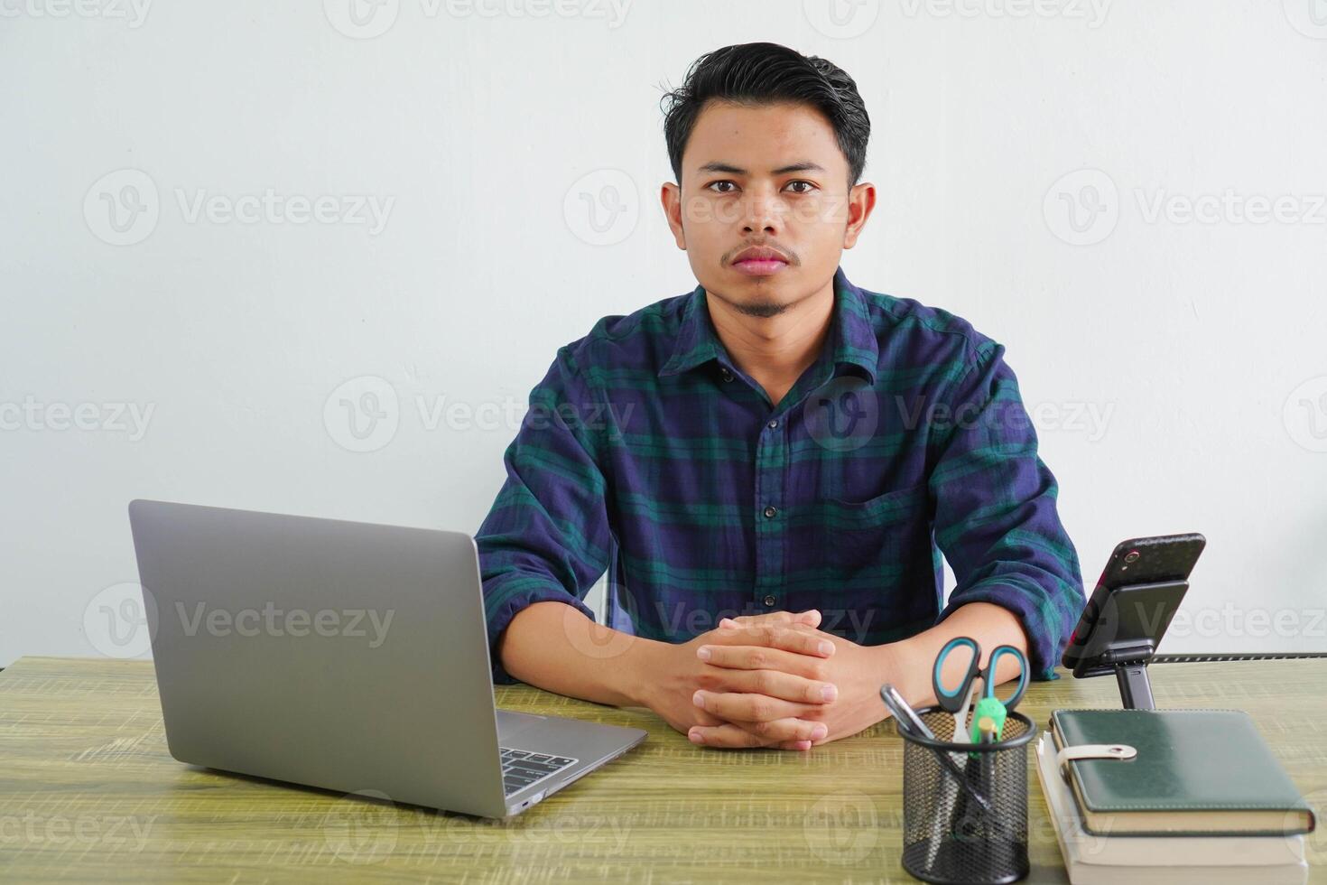 Successful young asian man in blue shirt sit work at wooden desk with pc laptop isolated on white background. Achievement business career lifestyle concept. looking camera photo