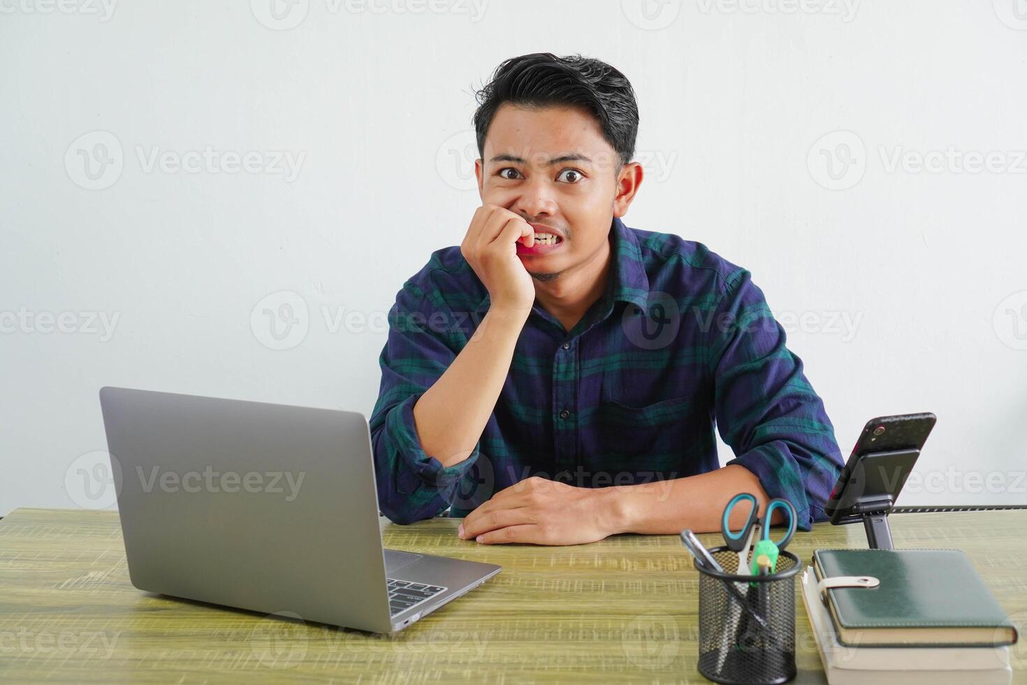 Nervous young asian man sit work at wooden desk with pc laptop. Achievement business career lifestyle concept. gnawing nails photo