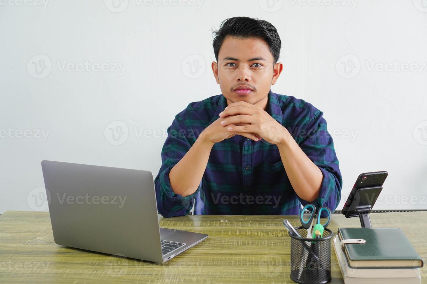 Successful young asian man in blue shirt sit work at wooden desk with pc laptop isolated on white background. Achievement business career lifestyle concept. looking camera photo