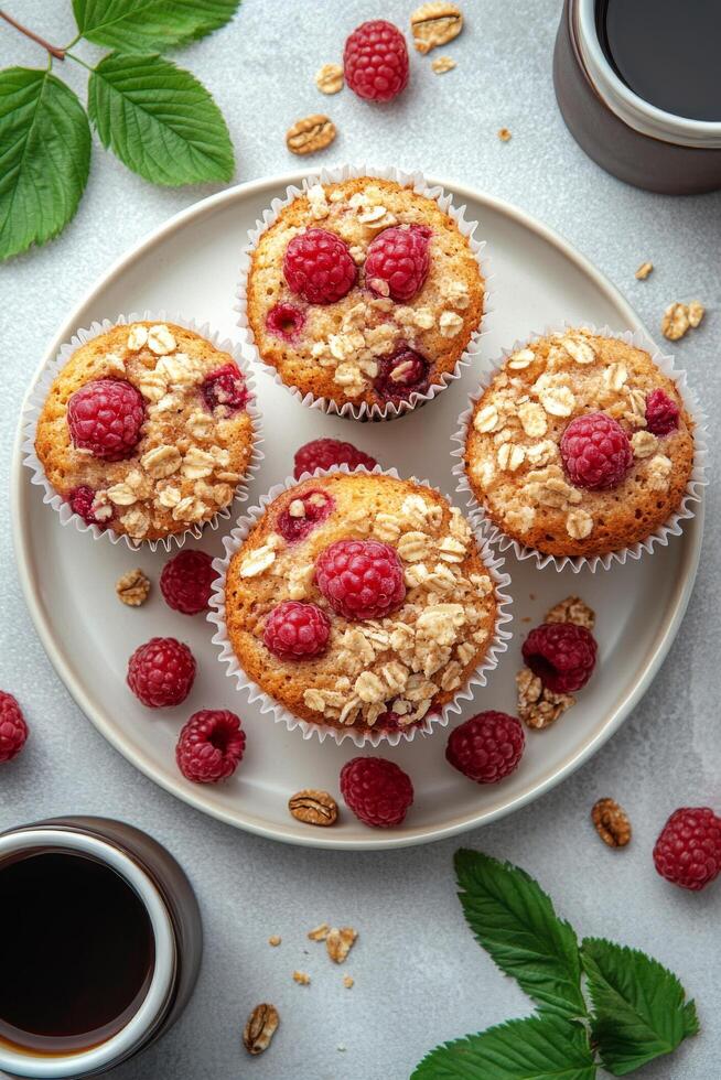 Freshly baked raspberry muffins with oats displayed on a plate surrounded by coffee photo