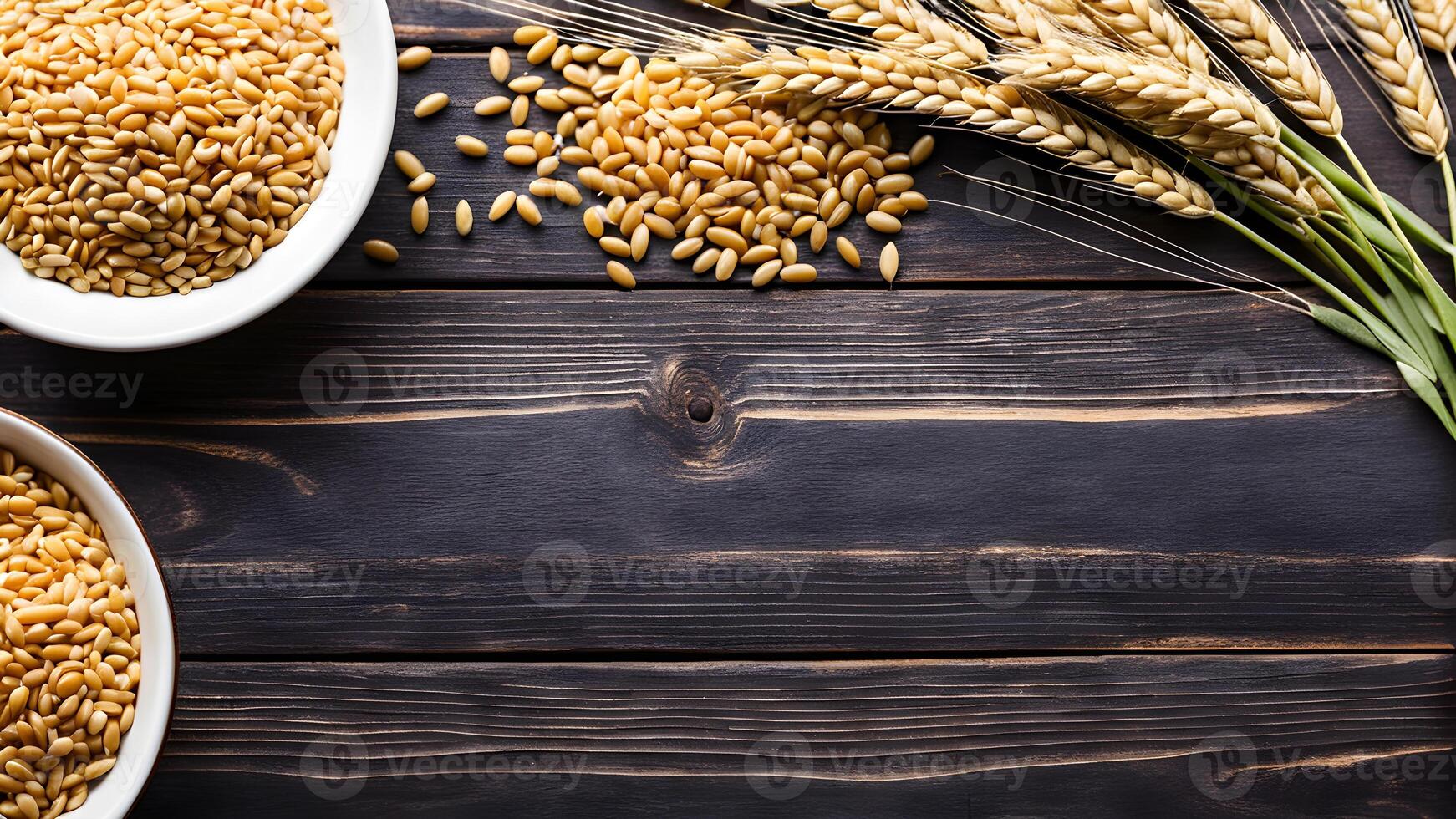 Top view of Wheat grain seeds in two ceramic bowls adorned by ear of wheat and seed heap on wooden table with blank space for design photo