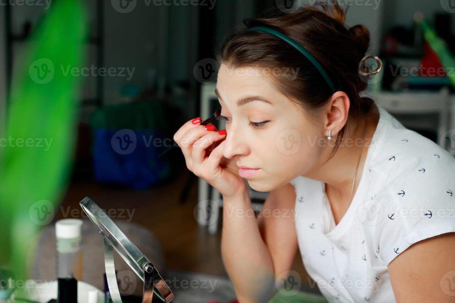 Young girl using brush to apply eyeshadow. Home makeup concept. Getting ready for a party photo
