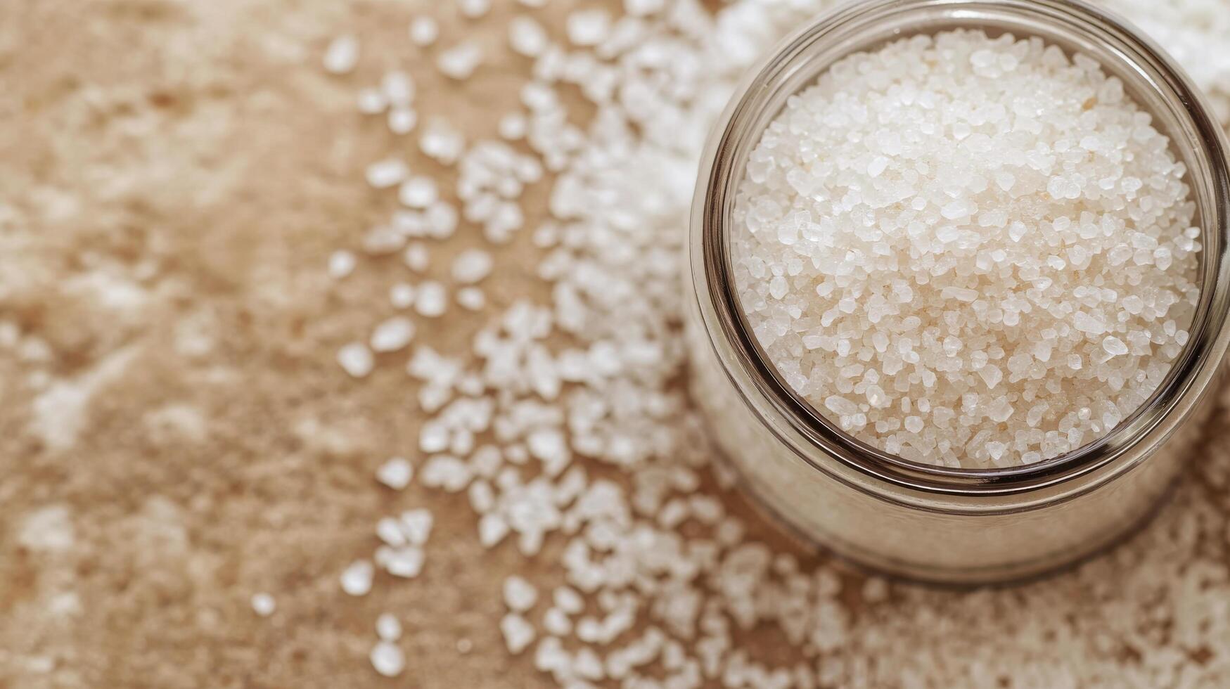 Freshly poured salt in a glass bowl on a rustic wooden table at home in natural lighting photo