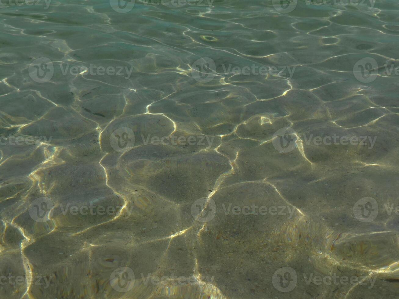 Crystal clear sea water through which you can see the bottom. Sunlight reflecting off the water. photo
