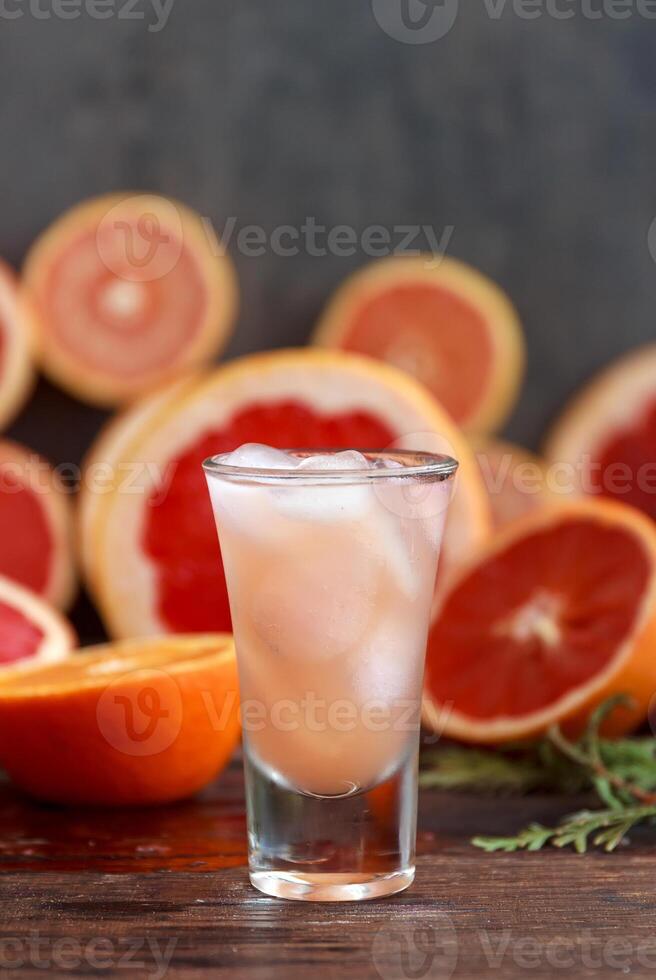 fresh grapefruits sliced and a tall glass filled with juice and vodka with ice photo