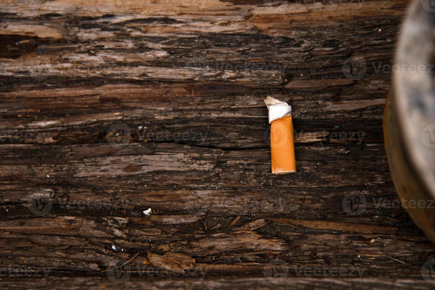 Closeup of an ashtray filled with numerous cigarette butts on a wooden surface, symbolizing smoking habits and litter, smoking harm, urban pollution, unhealthy lifestyle, littering. photo