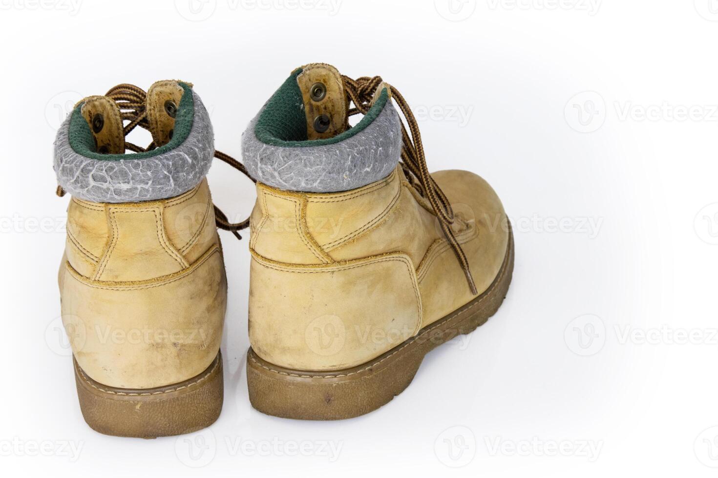 Vintage yellow leather hiking boots with laces in a worn look. Beige used military shoes with thick soles. Isolated on white background. Studio light. Copy space photo