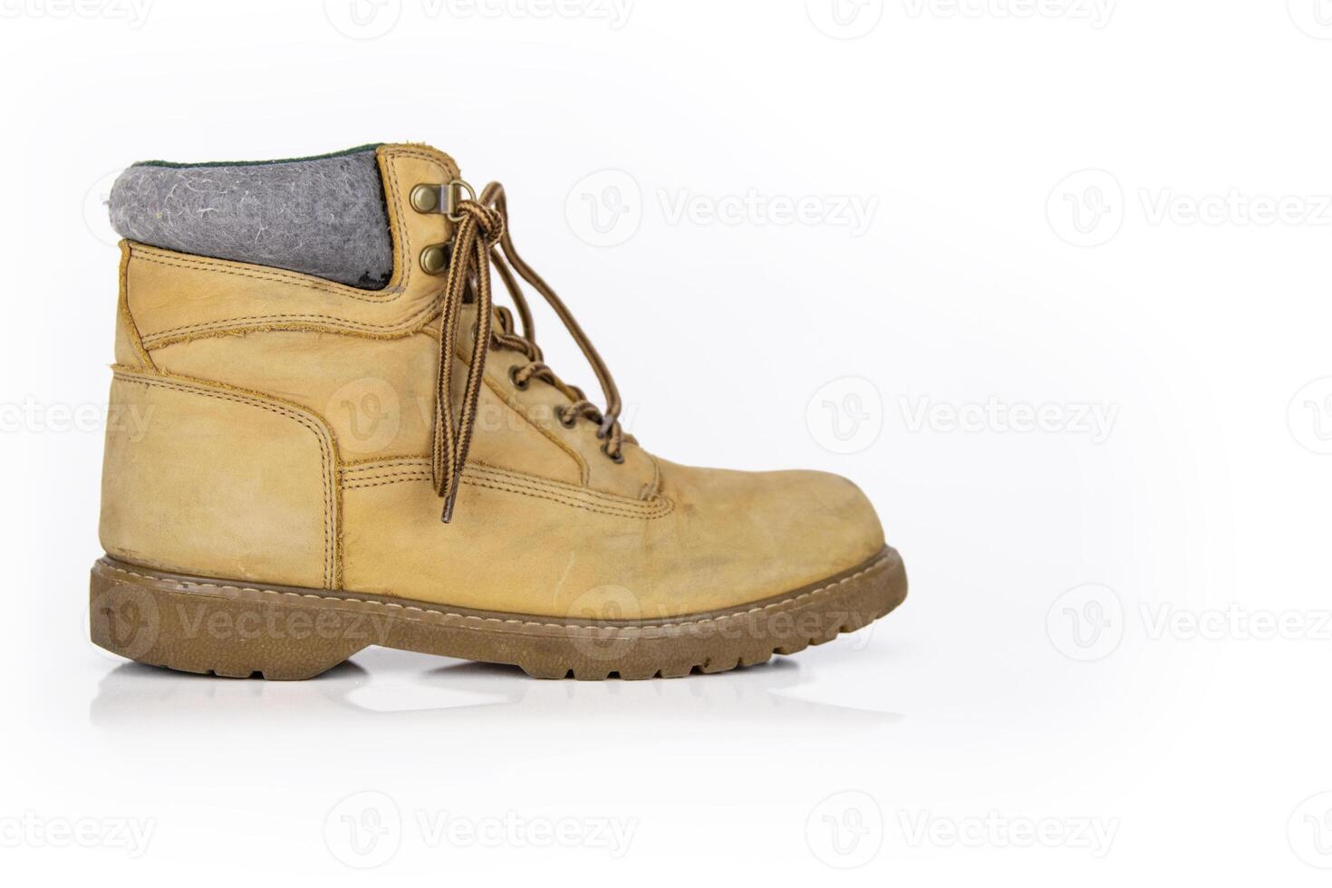 Single vintage durable yellow leather hiking boot with laces in a worn look. One beige used military shoe with thick sole. Isolated on white background. Studio light. Copy space photo
