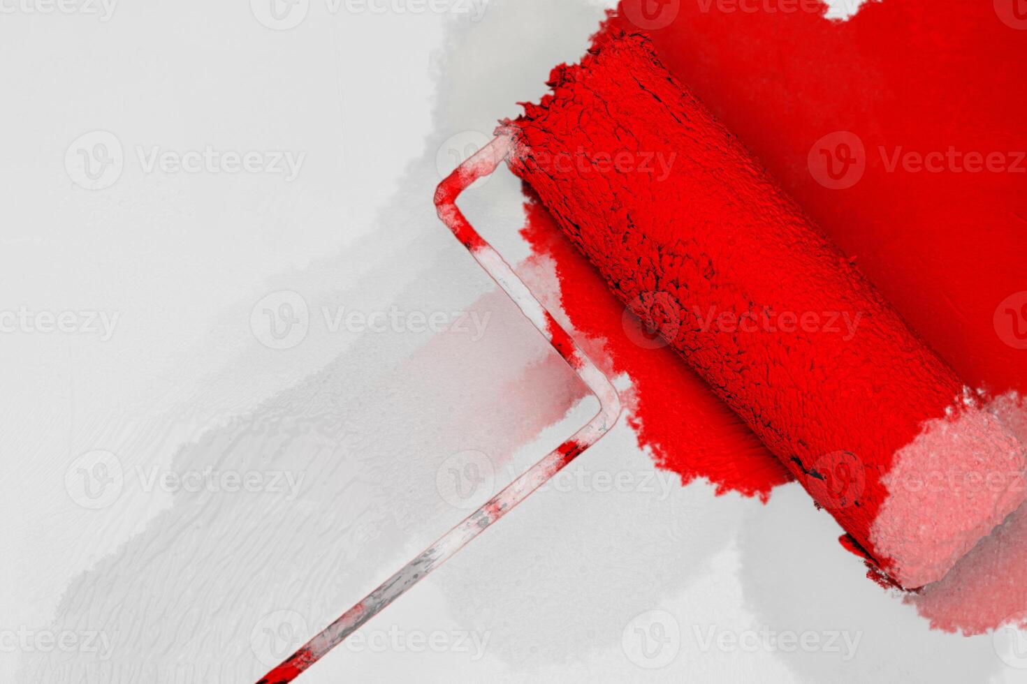 Creative graphic concept of paint roller applying fresh red color paint onto the white concrete wall. Process of home renovation, improvement and makeover. Copy space. photo
