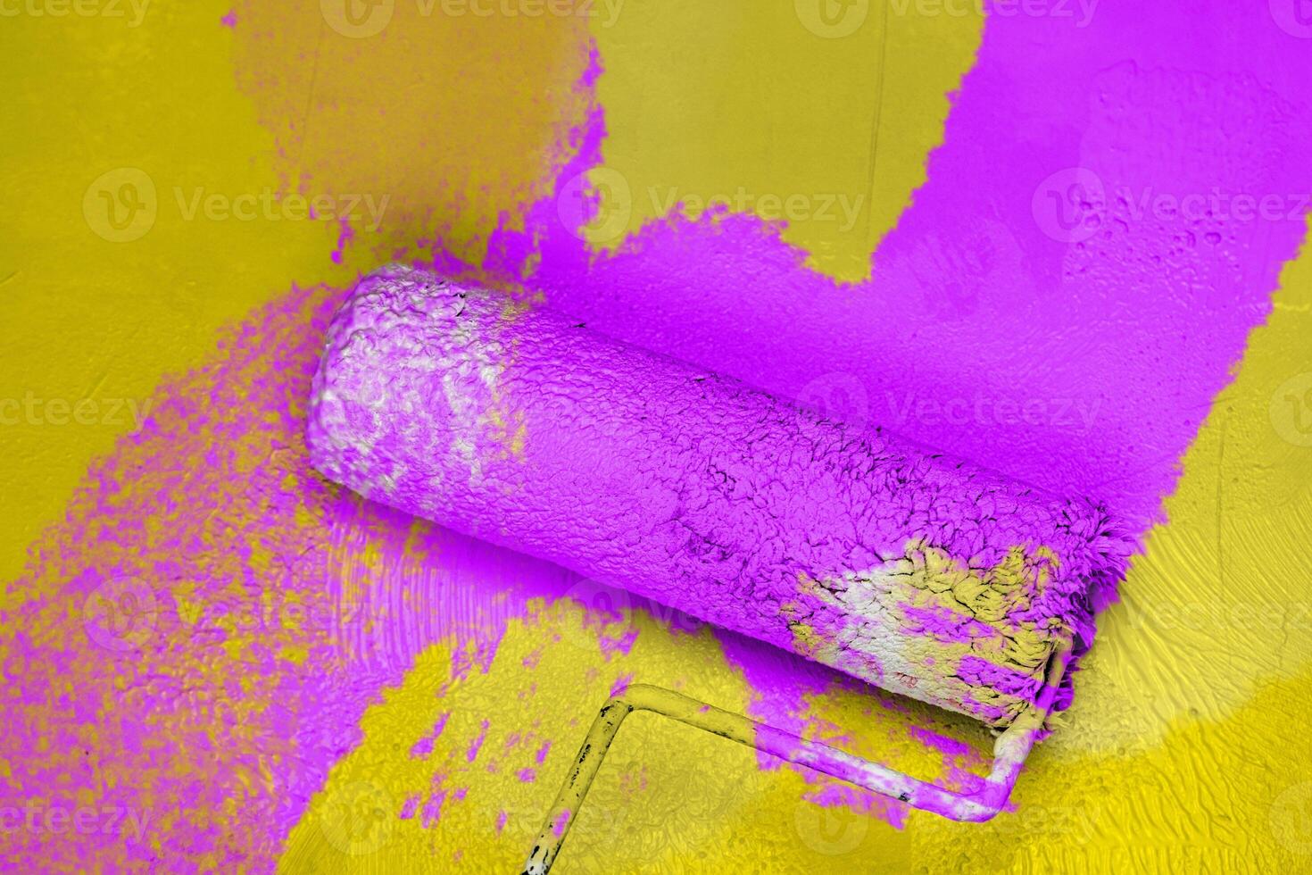 Creative graphic concept of paint roller applying fresh purple lilac paint onto the yellow color concrete wall. Process of home renovation, improvement and makeover. Copy space. photo