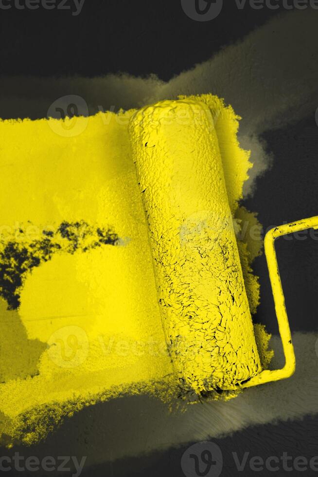Creative graphic concept of paint roller applying fresh orange yellow color paint onto the gray white concrete wall. Process of home renovation, improvement and makeover. Copy space. photo