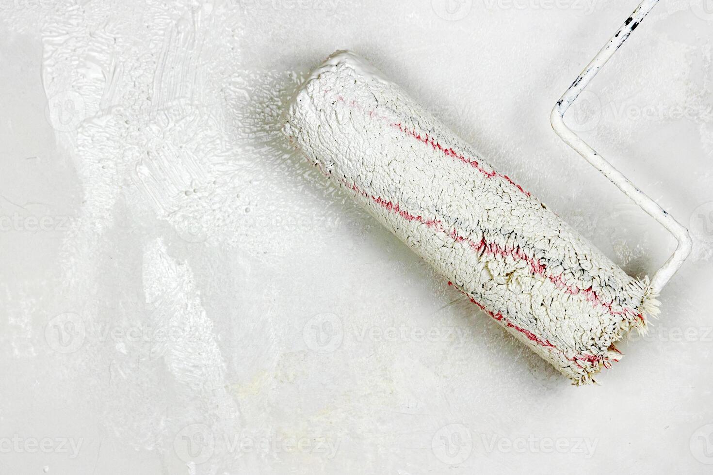 Closeup of a paint roller applying fresh white paint on a wall. DIY process of home renovation and painting for a clean, updated interior. home improvement and wall makeover. Copy space. photo