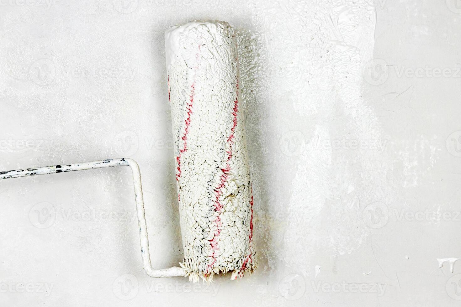 Closeup of a paint roller applying fresh white paint on a wall. DIY process of home renovation and painting for a clean, updated interior. home improvement and wall makeover. Copy space. photo
