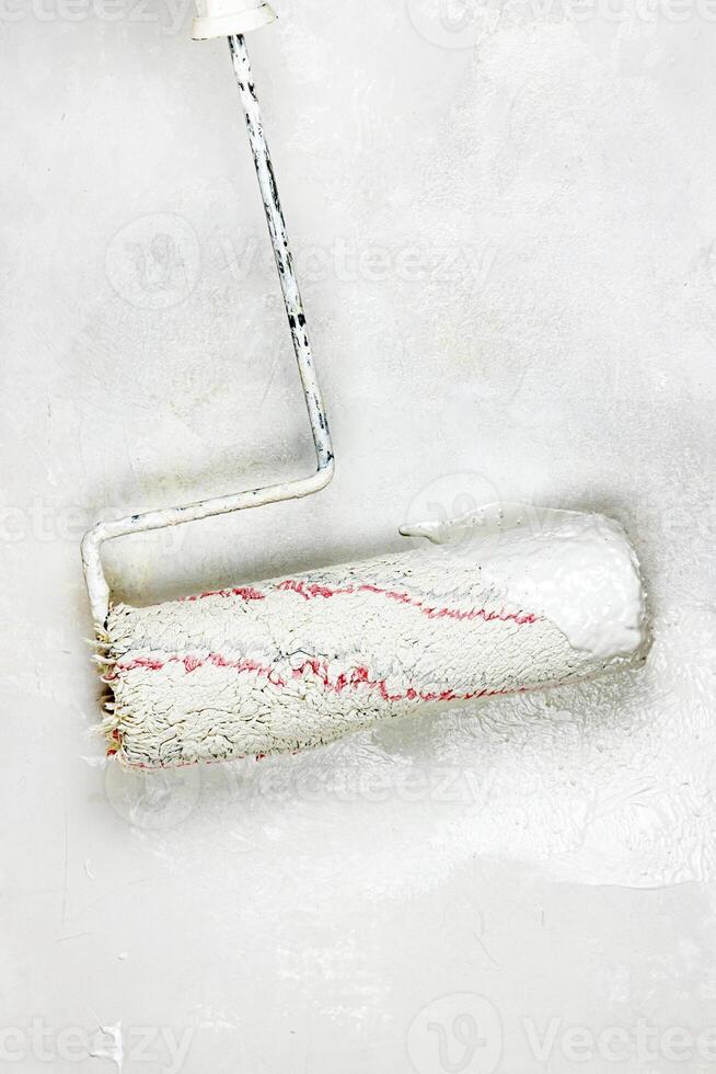 Closeup of a paint roller applying fresh white paint on a wall. DIY process of home renovation and painting for a clean, updated interior. home improvement and wall makeover. Copy space. photo