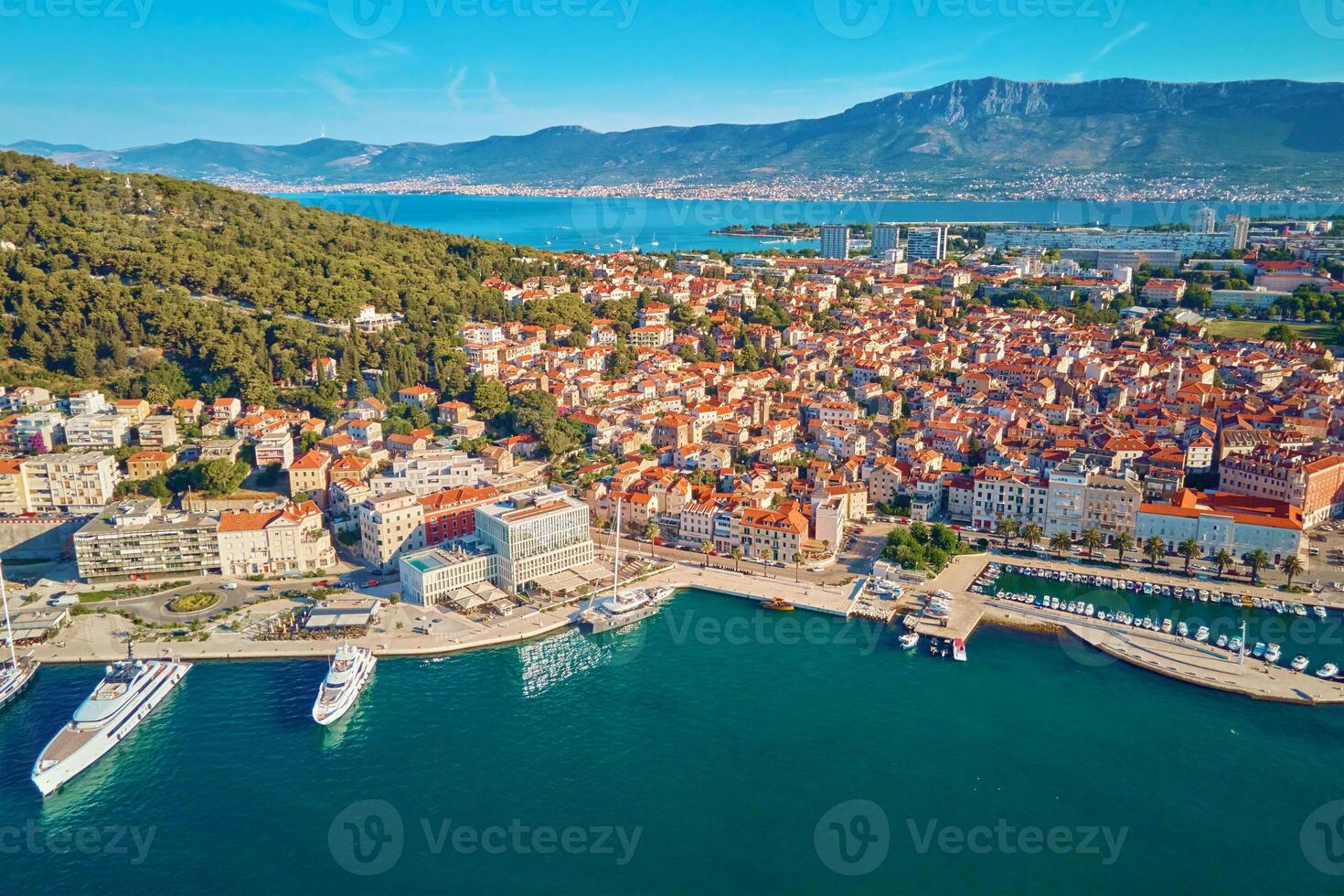 Aerial view of Split, Croatia. Cityscape of coastal touristic city with harbor with mountains in background. Old town with historical red roof tiled buildings near Adriatic Sea photo