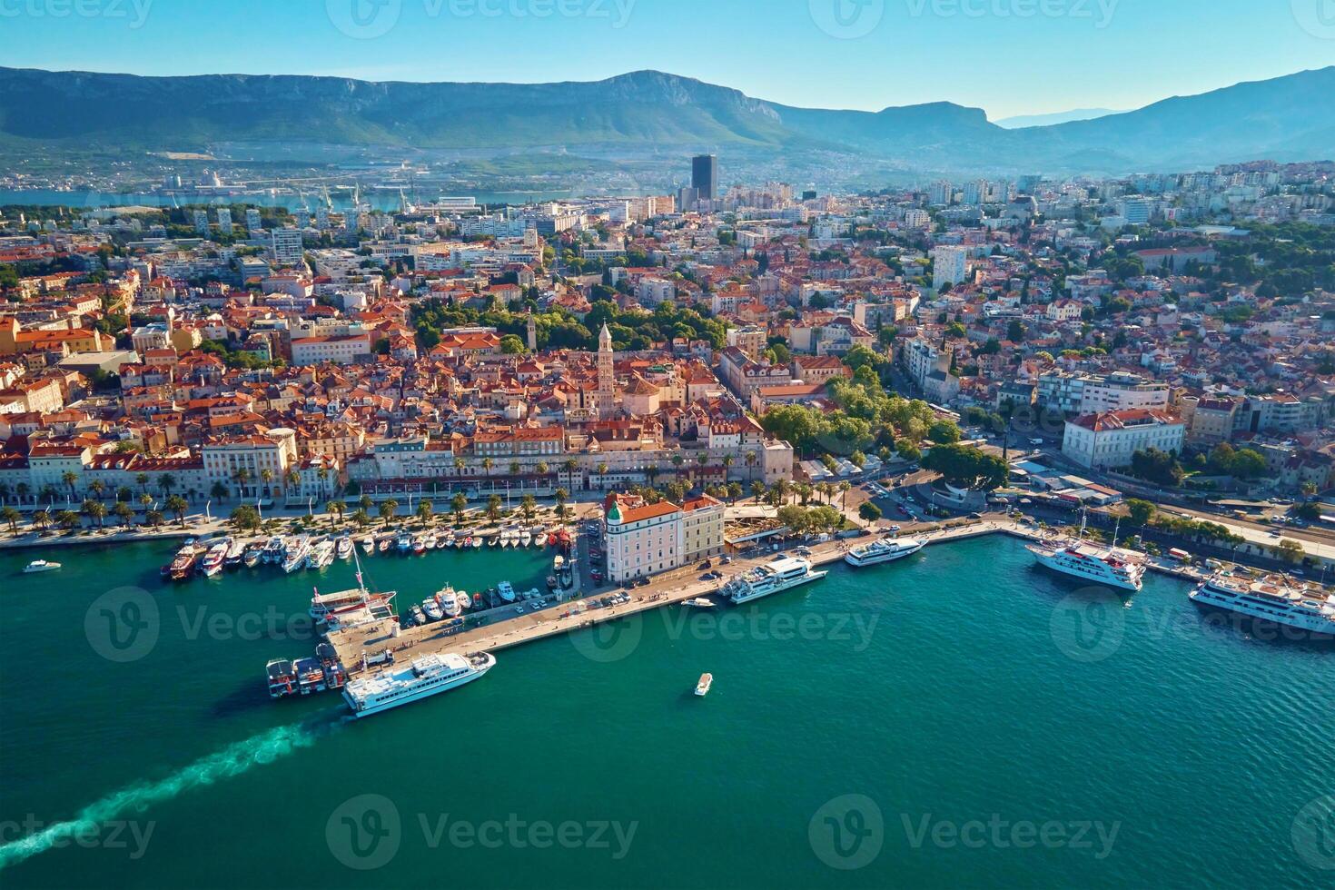 Aerial view of Split, Croatia. Cityscape of coastal touristic city with harbor with mountains in background. Old town with historical red roof tiled buildings near Adriatic Sea photo