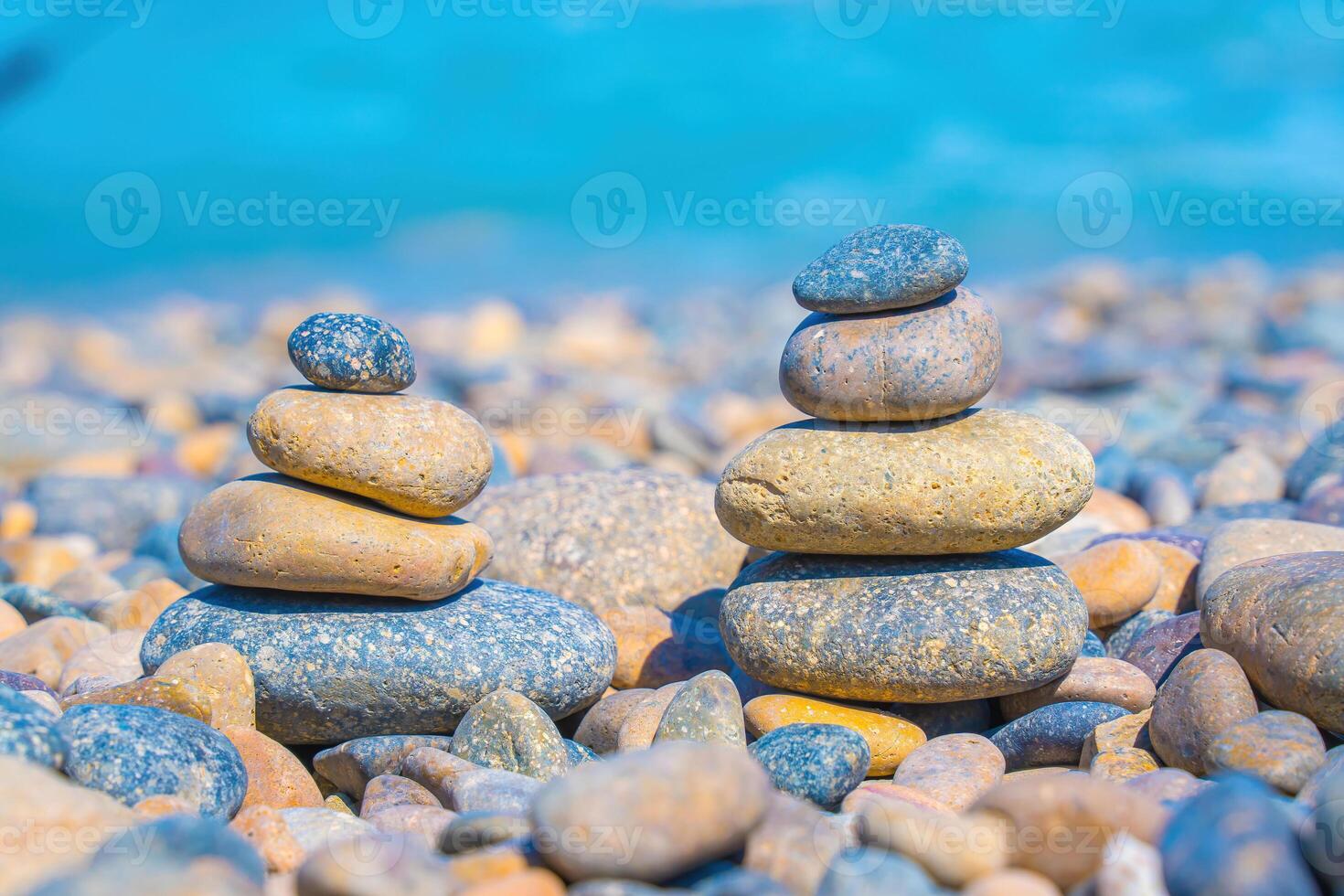Symbolic scales of stones against the background of the sea and blue sky. Concept of harmony and balance. Pros and cons concept. Pyramid stones balance on the sand of the beach with blurred background photo