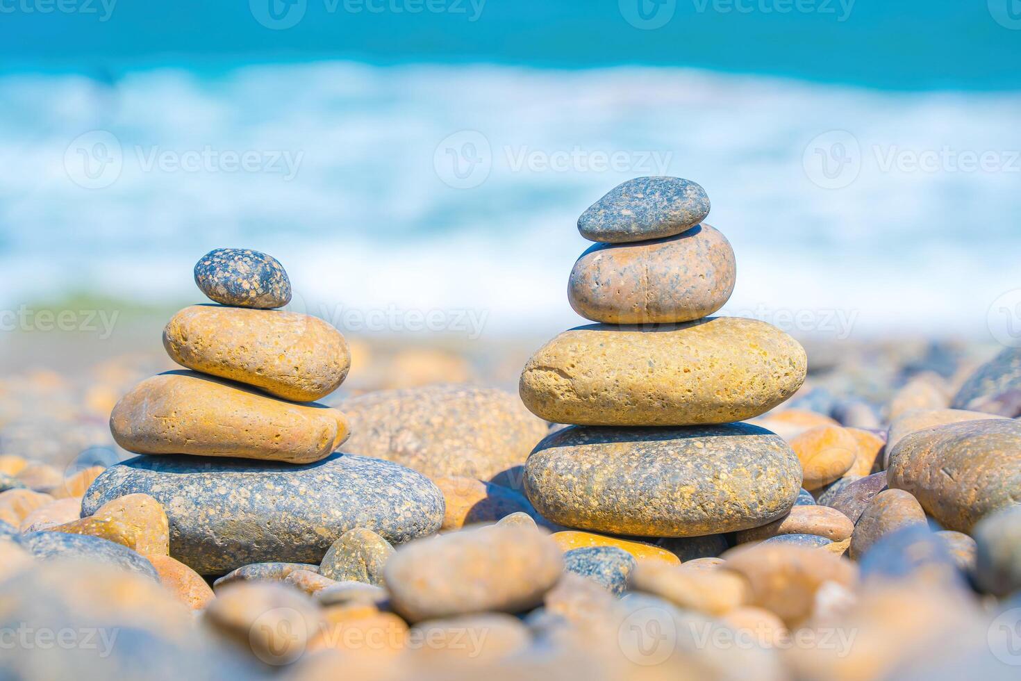 Symbolic scales of stones against the background of the sea and blue sky. Concept of harmony and balance. Pros and cons concept. Pyramid stones balance on the sand of the beach with blurred background photo