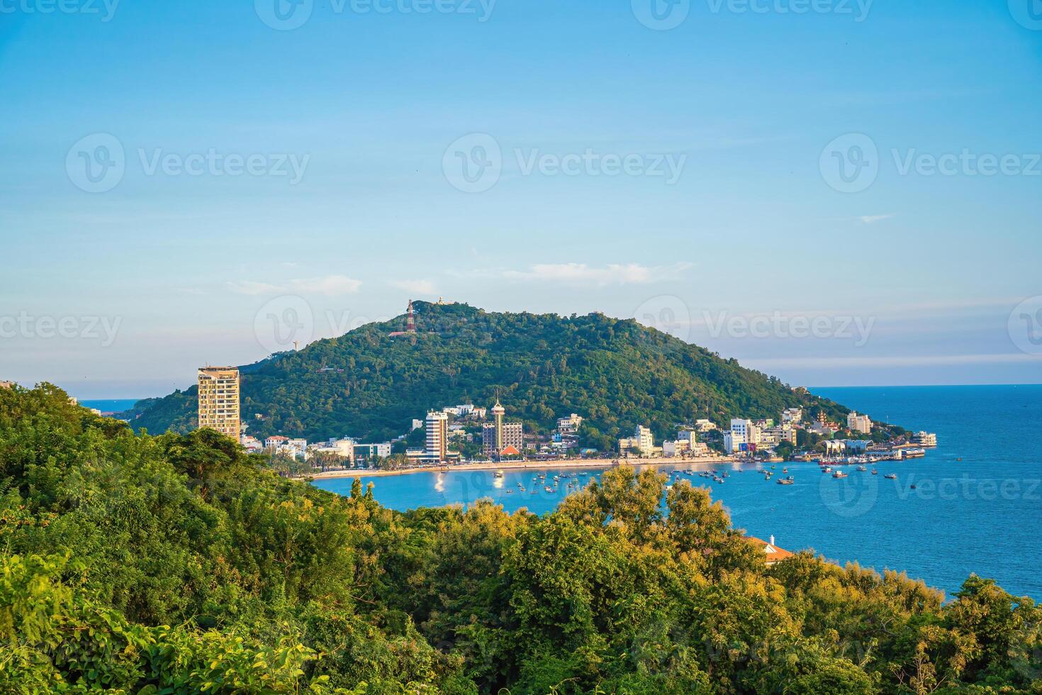 Vung Tau city aerial view with beautiful sunset and so many boats, cable car. Panoramic coastal Vung Tau view from above, with waves, coastline, streets, coconut trees and Tao Phung mountain photo