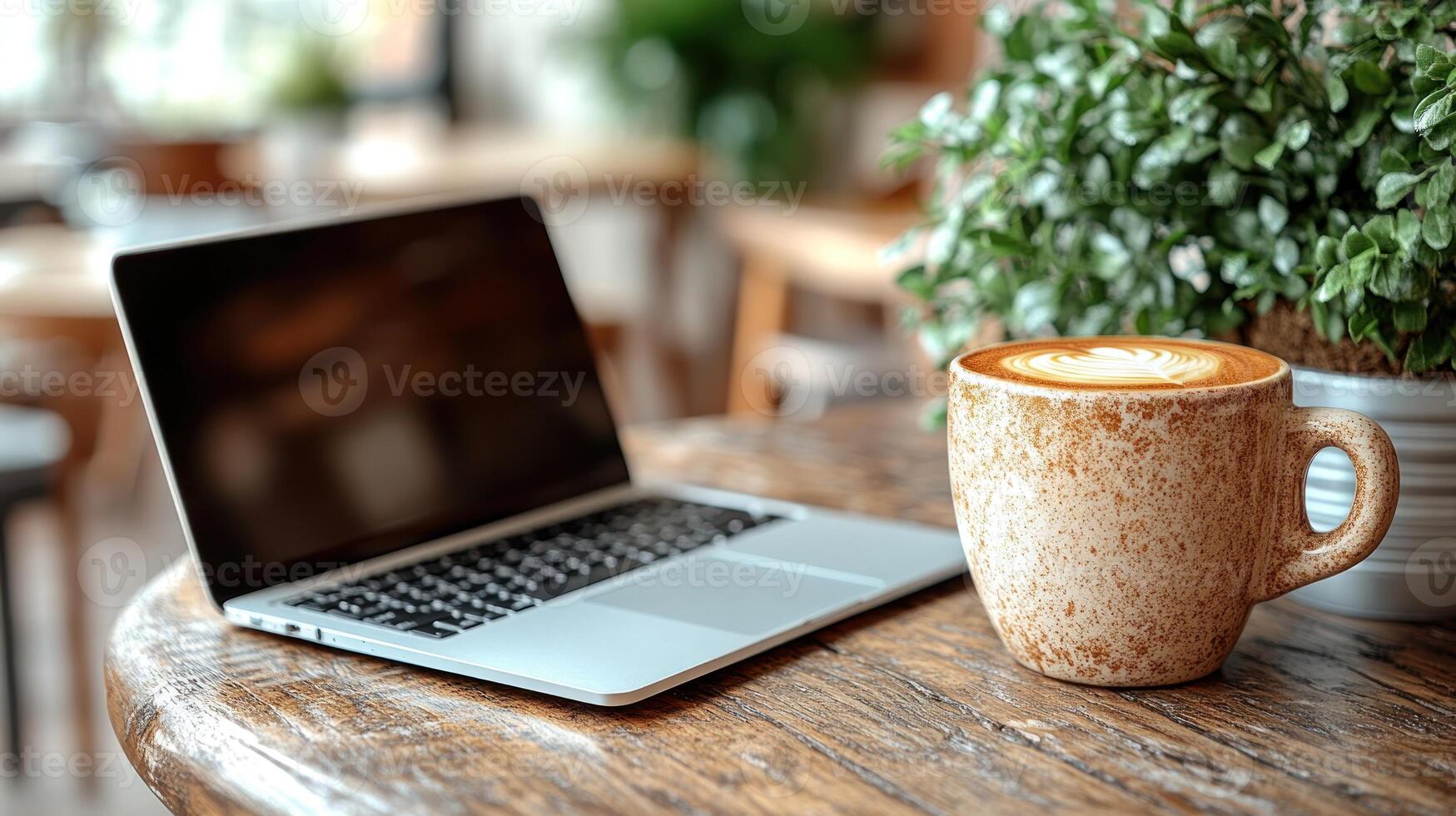 A warm latte rests beside a sleek laptop, creating an inviting workspace atmosphere photo