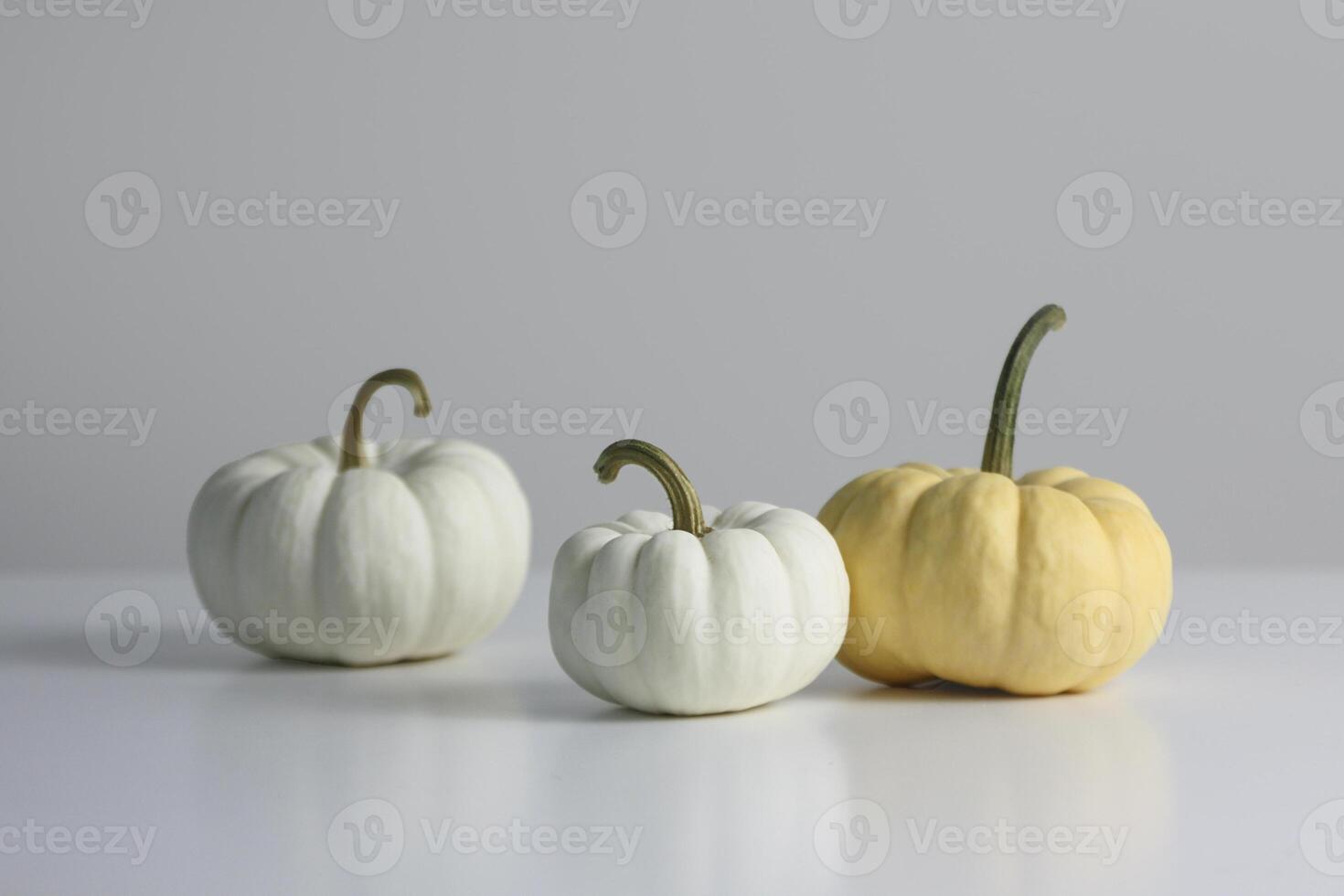 Three decorative pumpkins in various colors displayed on a light surface for autumn decor photo