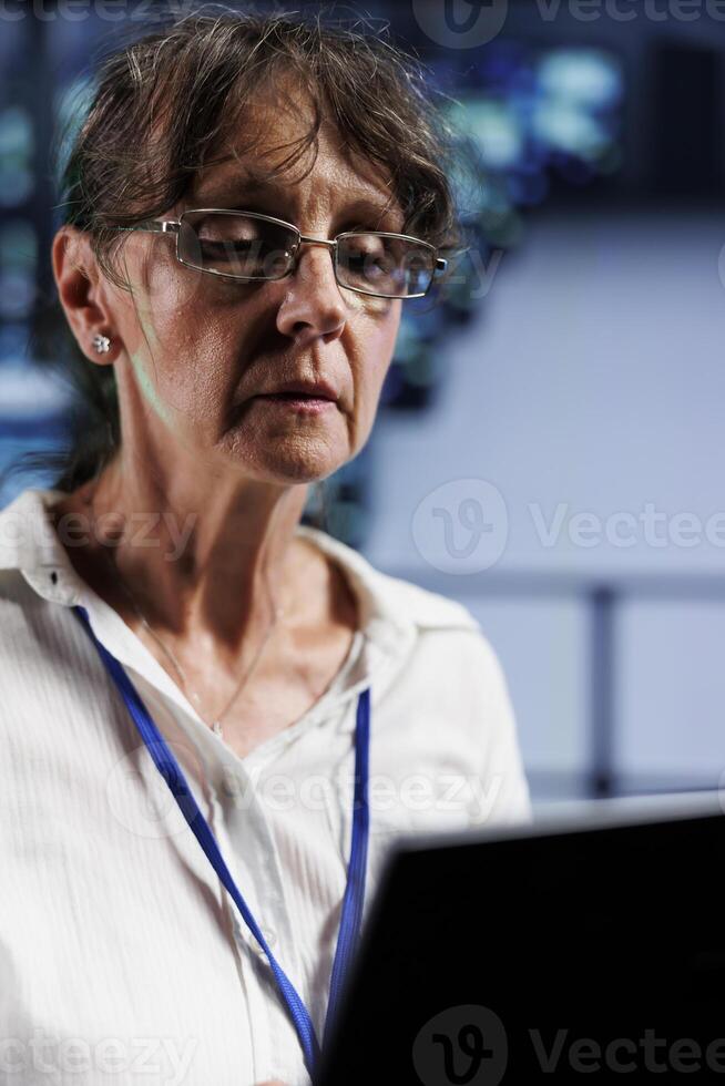 Senior IT programmer in data center working on laptop, setting up high bandwidth dedicated multiplayer gaming servers to accommodate more traffic from worldwide locations and avoid disruptive lag photo