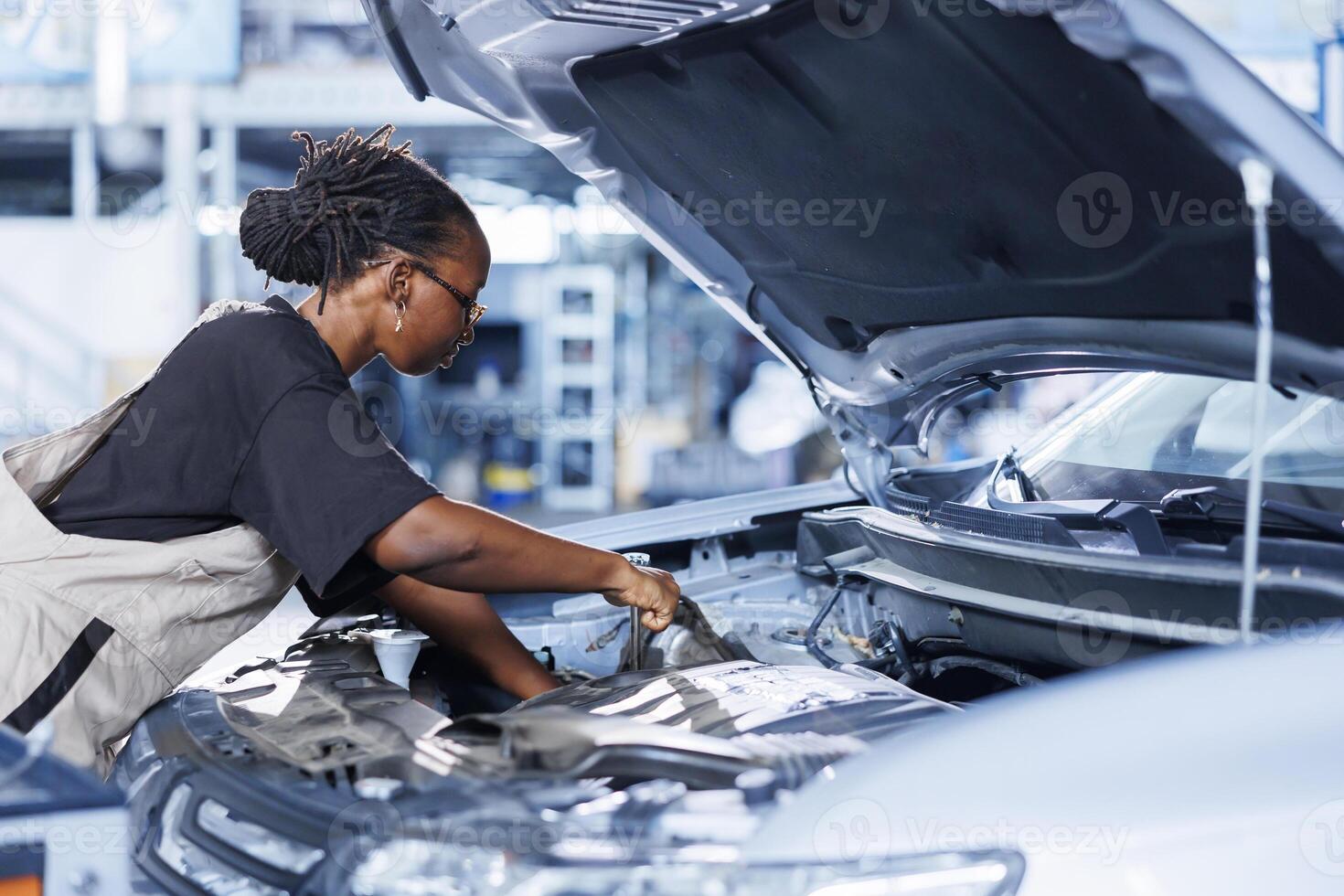 Auto repair shop mechanic expertly examines car engine using advanced mechanical tools, ensuring seamless automotive performance. Efficient professional in garage conducts routine vehicle checkup photo