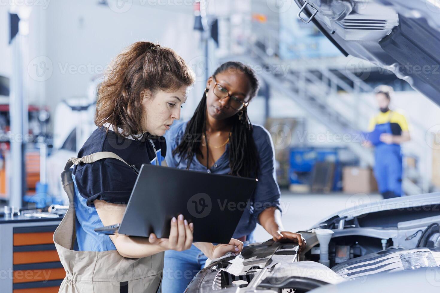 Mechanic in car service ordering new engine for damaged vehicle using laptop. Employee next to client looking online for components to replace old ones in malfunctioning automobile photo